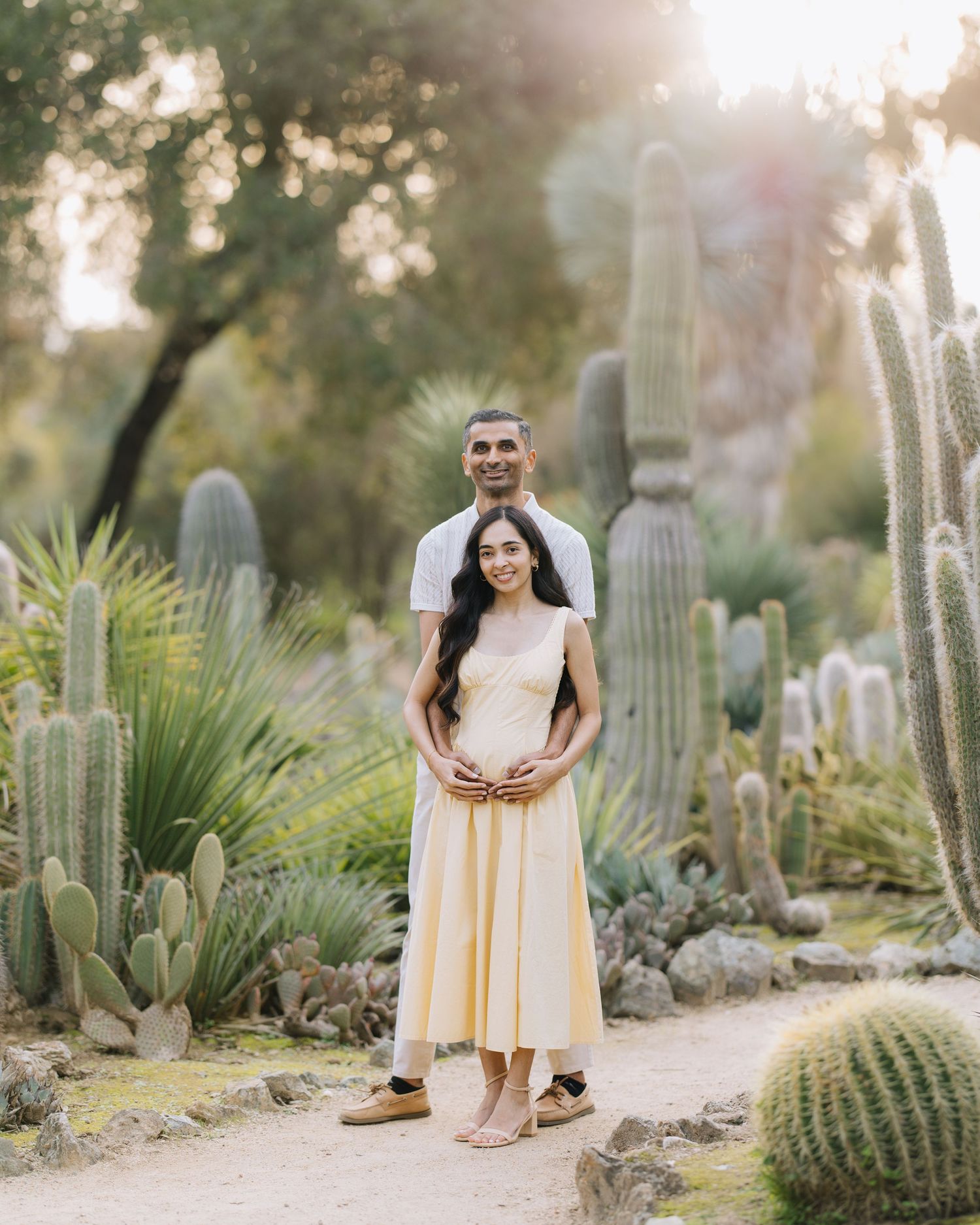 Pregnant couple posing together in a stunning desert cactus garden at golden hour at Stanford Arizona Garden maternity photoshoot.