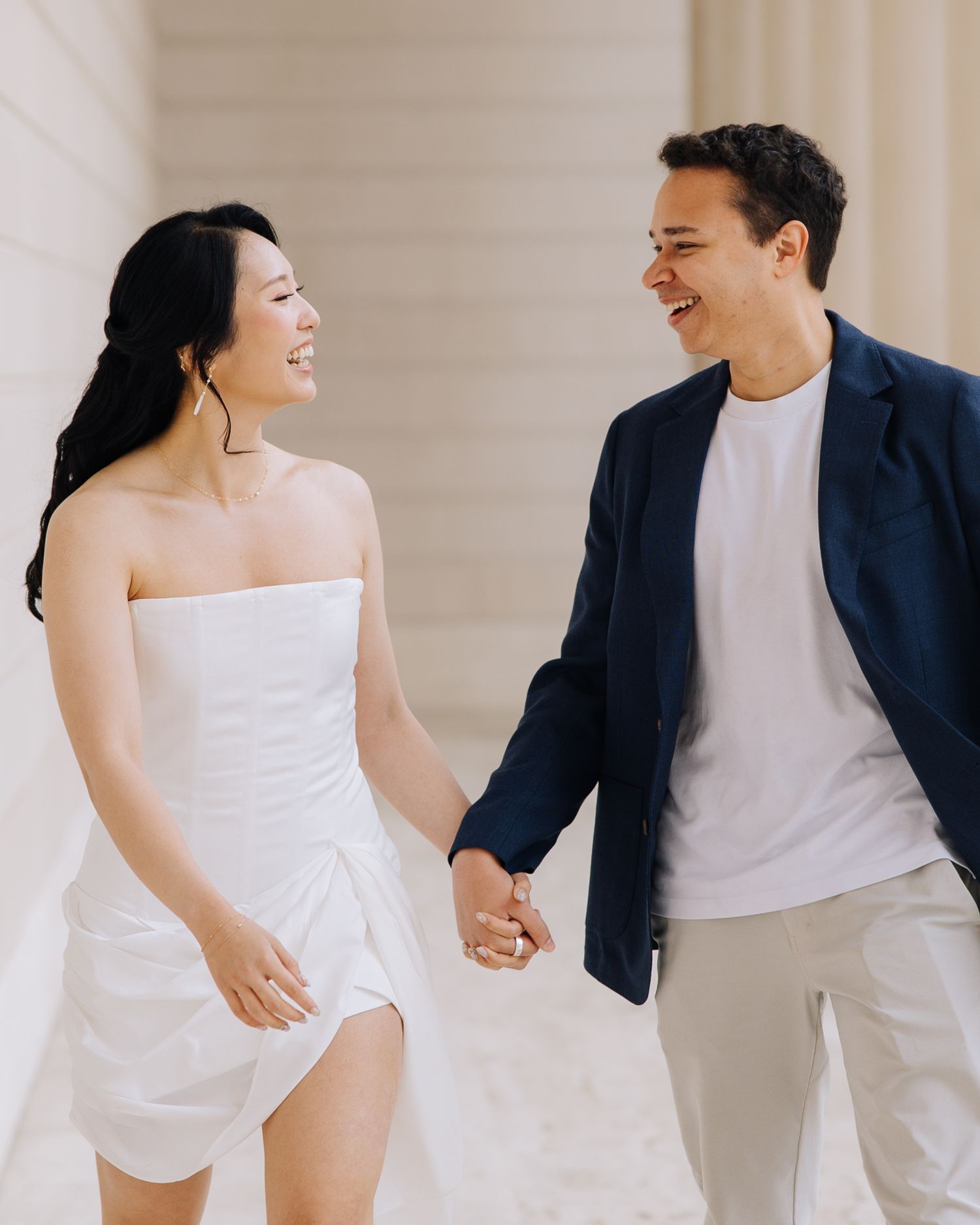 Happy couple holding hands and laughing during engagement photoshoot at Legion of Honor museum in SF.