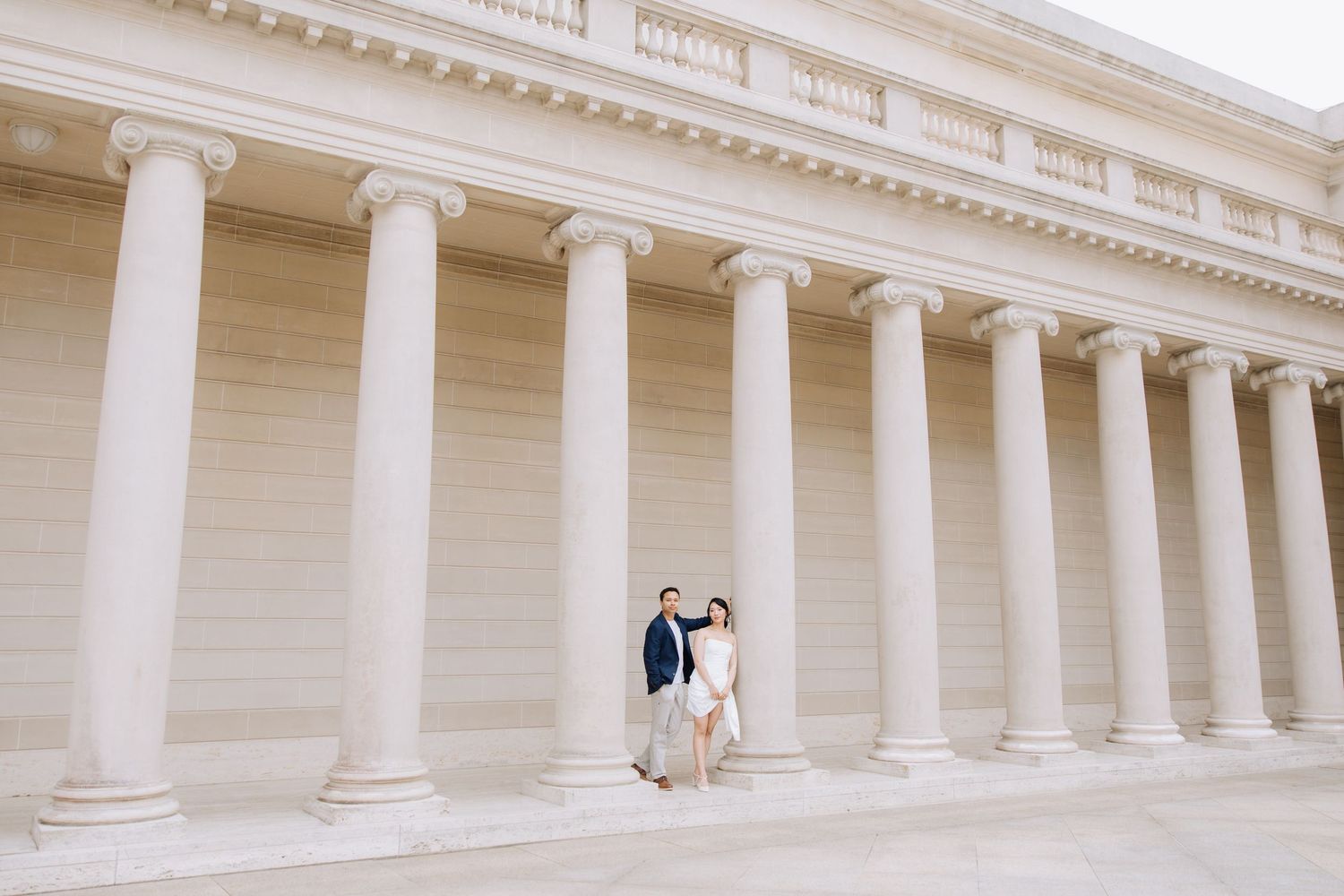 Couple posing in front of grand white columns at a neoclassical building, perfect for elegant engagement photos at Legion of Honor museum.