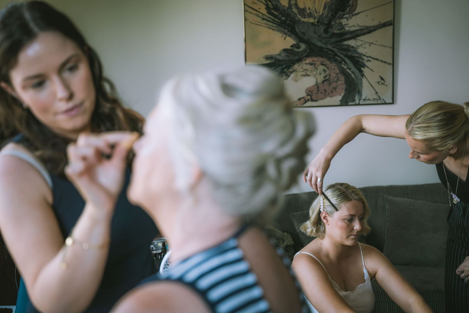 Bridesmaids and stylists help prepare the bride with hair and makeup before the wedding ceremony in an AirBnb in Kendal