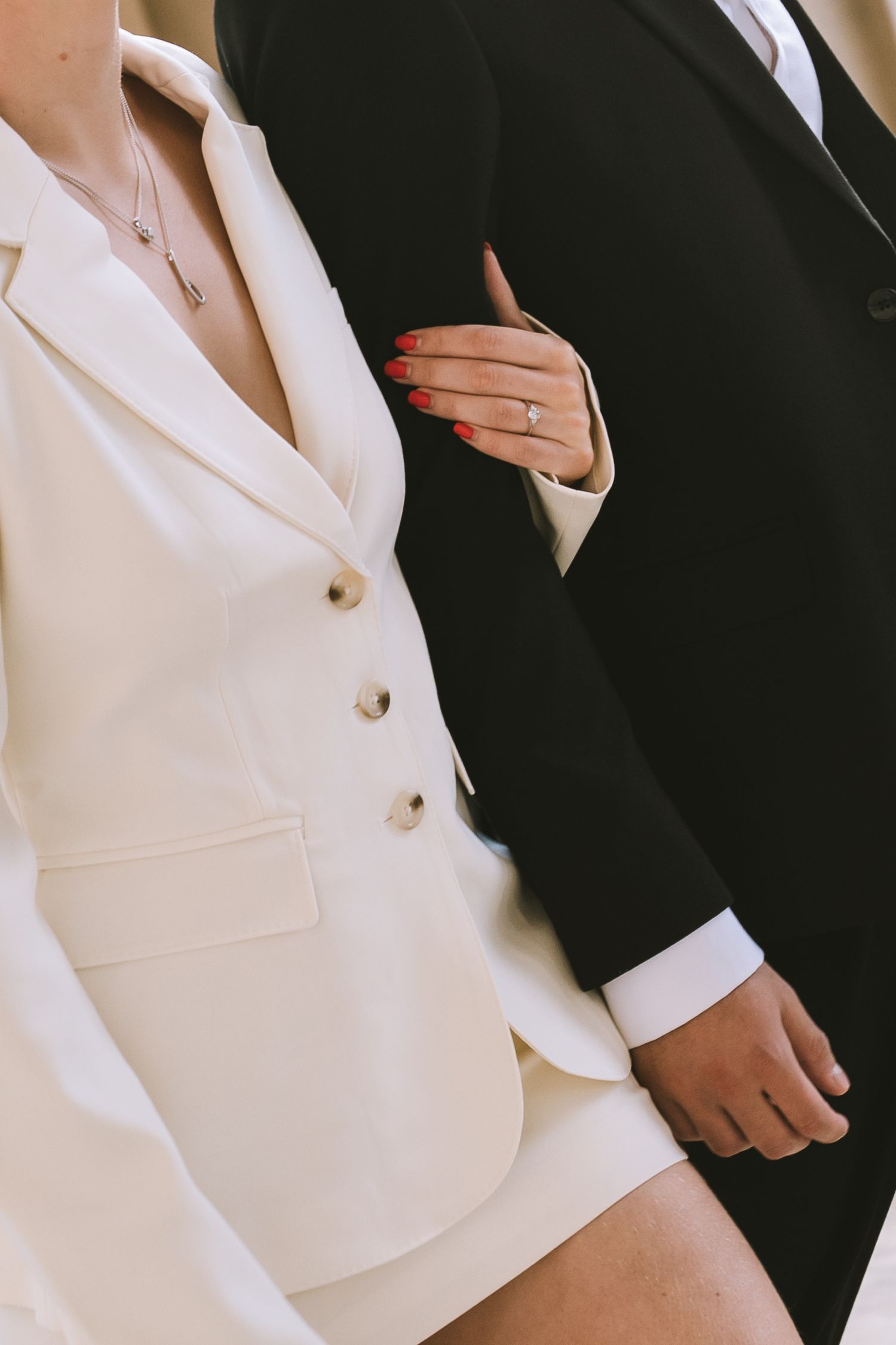 Close-up of bride in white blazer co ord dress holding grooms arm showing diamond engagement ring in Liverpool at St Georges Hall