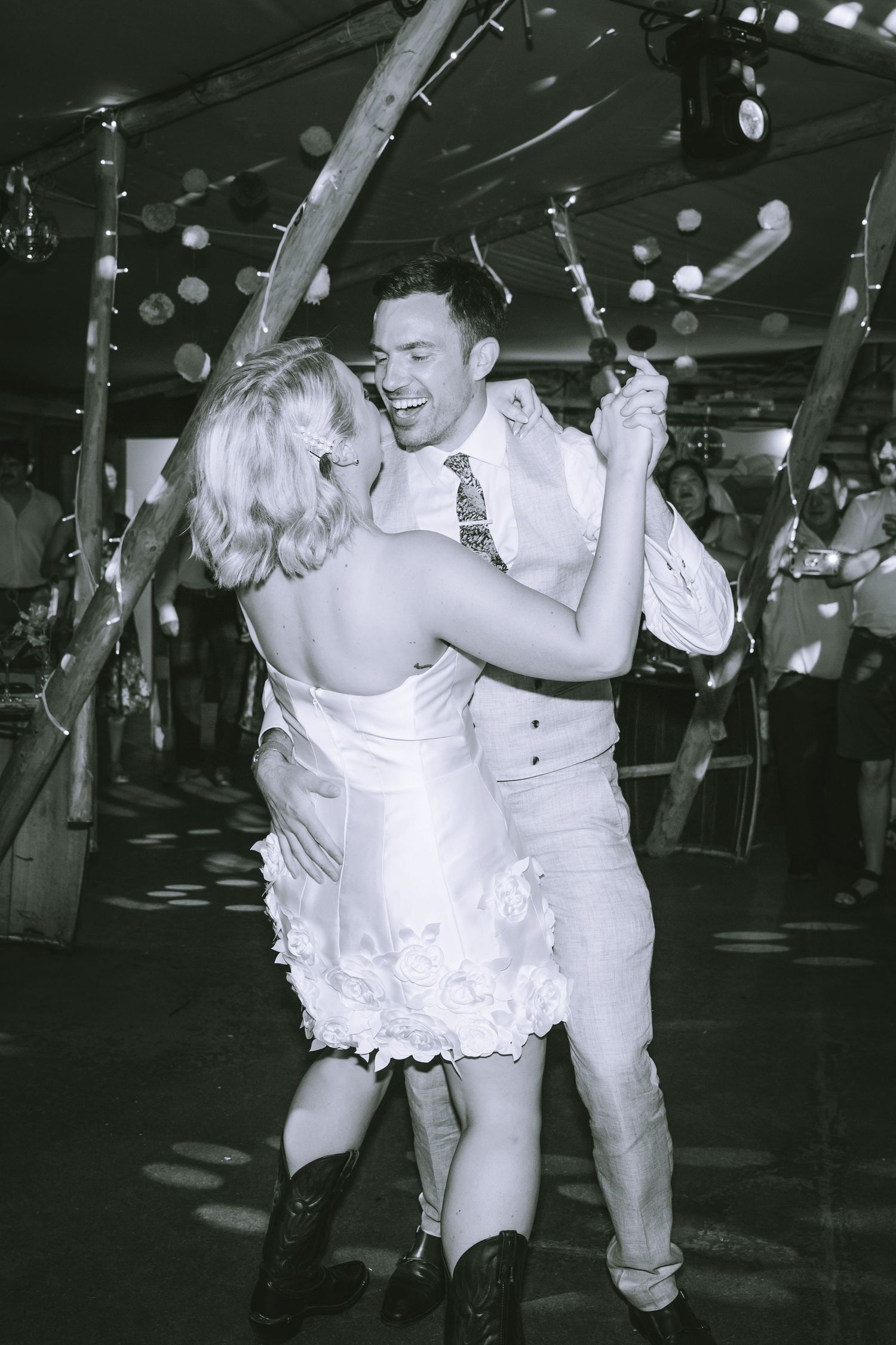 Bride and groom share a lively first dance in black and white at their festive tipi wedding reception in Kendal, The Lake District