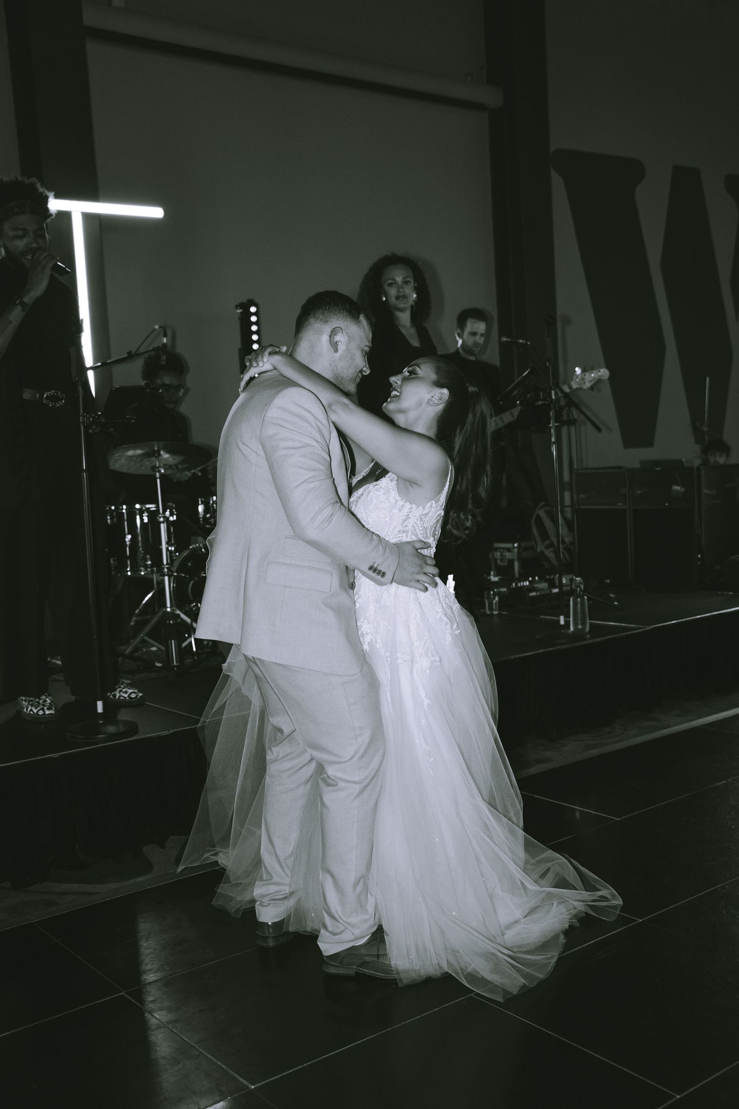 Black and white photo of newlyweds sharing romantic first dance with live band performing behind them in Liverpool at the Titanic Hotel
