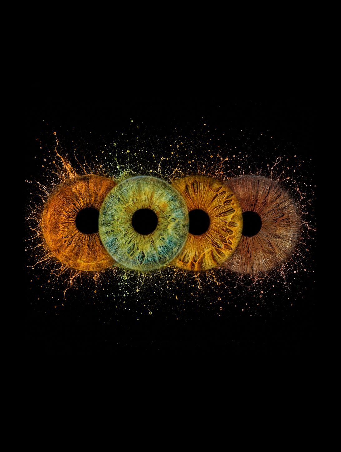 Three vibrant human irises in orange, green, and amber exploding with colorful particles on black background.