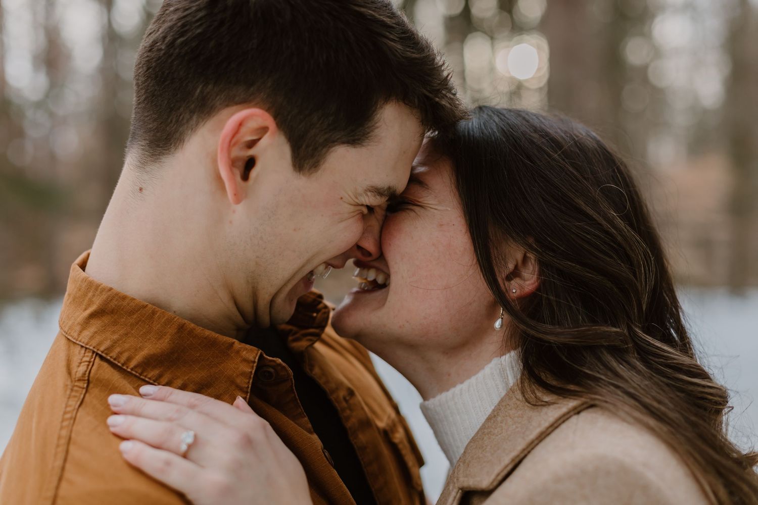 A couple shares a tender romantic moment in a forest setting during golden hour.