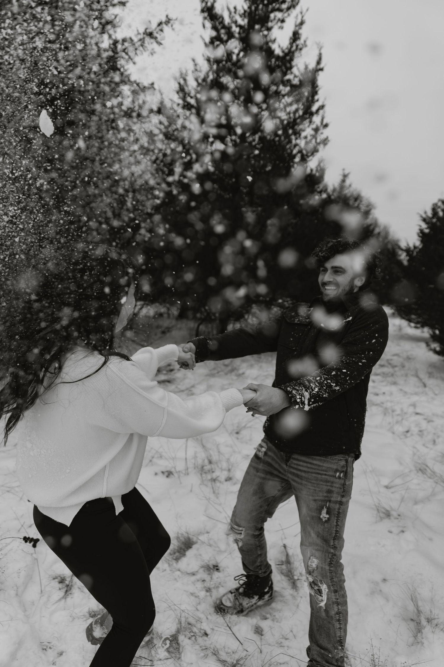 A playful snowball fight sequence captured in black and white photography showing figures throwing snow at each other.