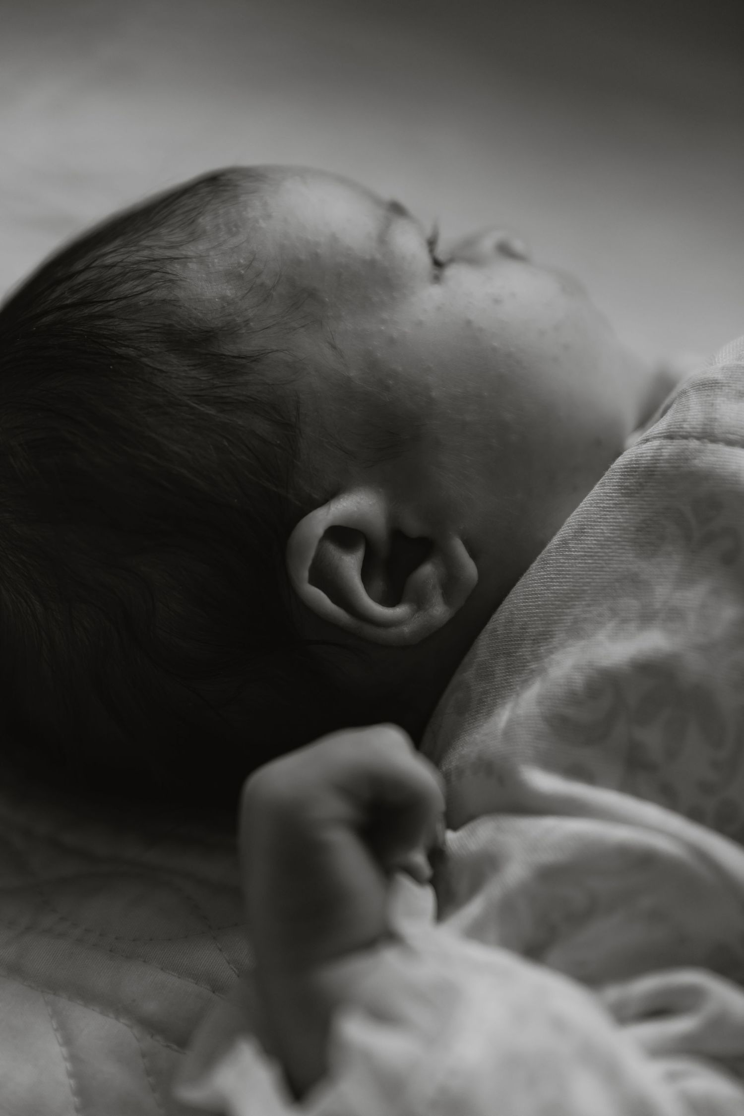 Black and white artistic photo sequence showing a sleeping baby's profile and features in soft focus.