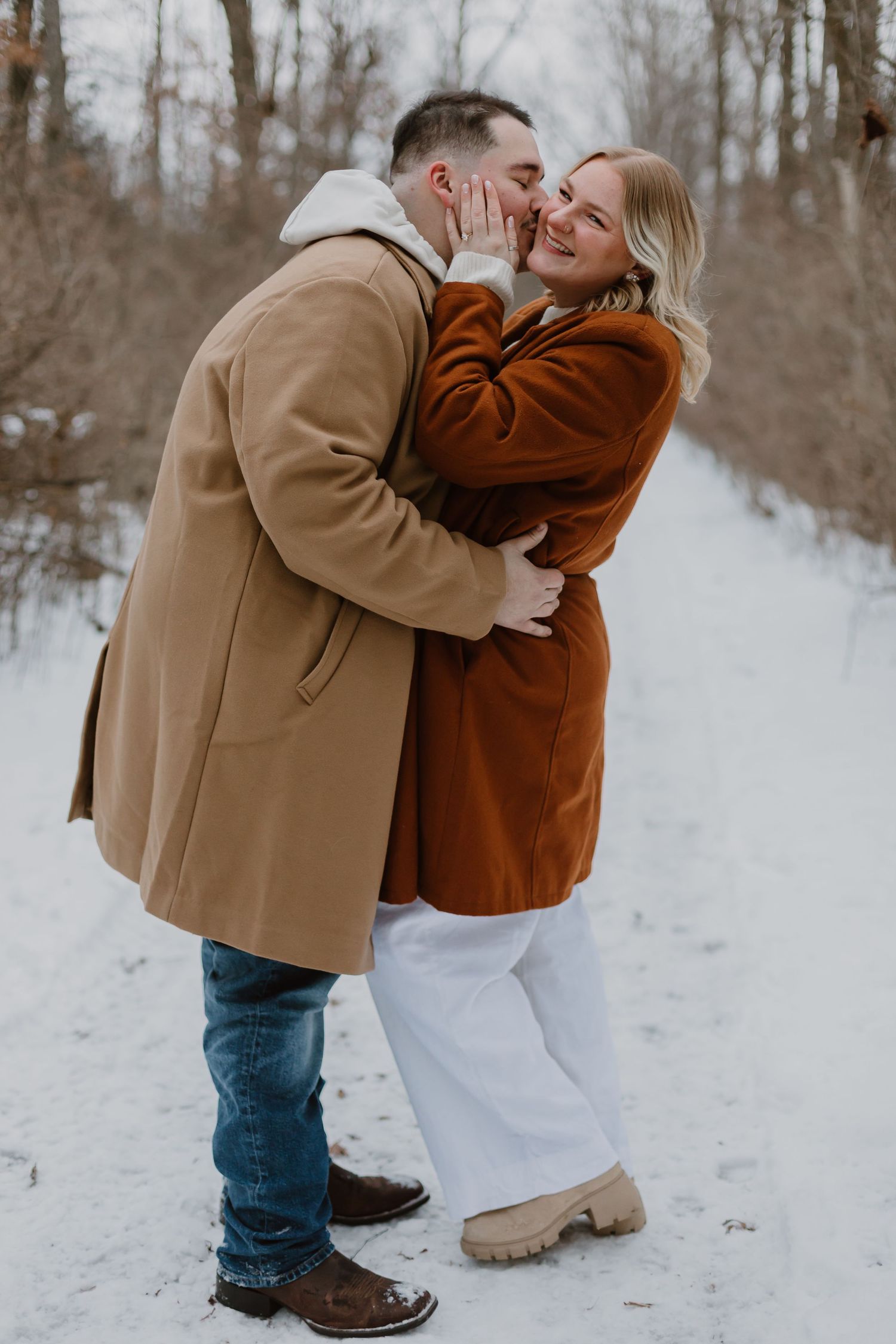 A joyful winter scene showing a couple laughing and embracing in the snow.