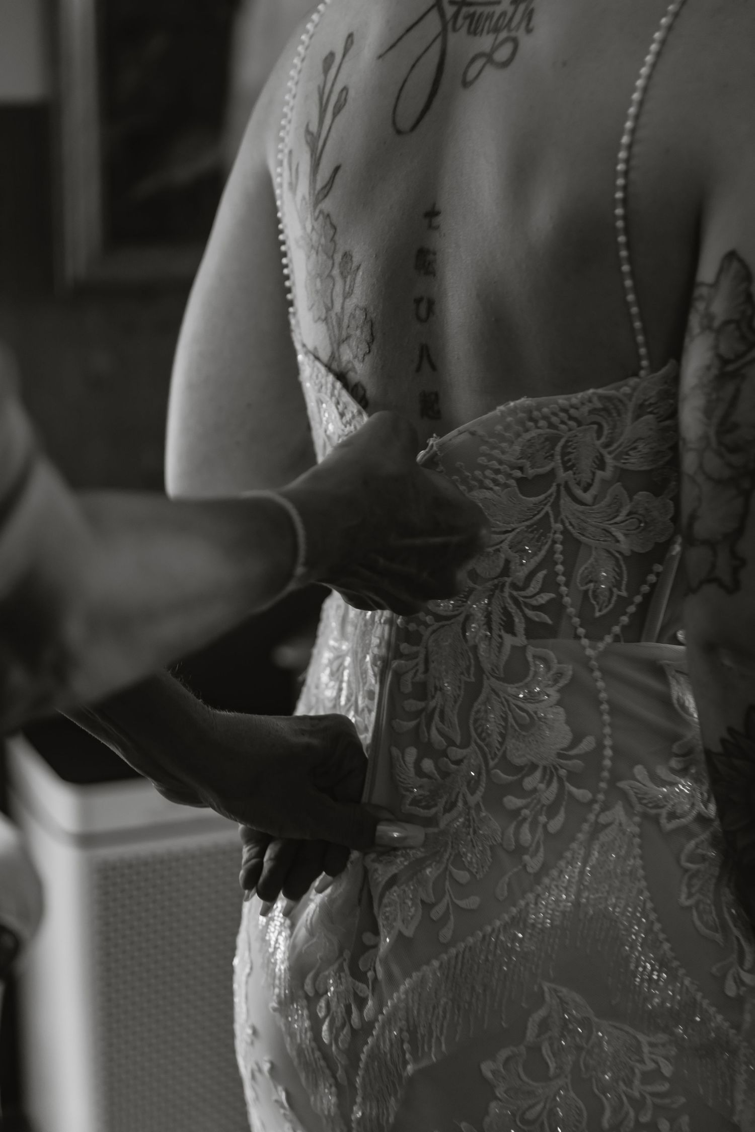 Close-up black and white detail of intricate lace and beading on a wedding dress bodice.