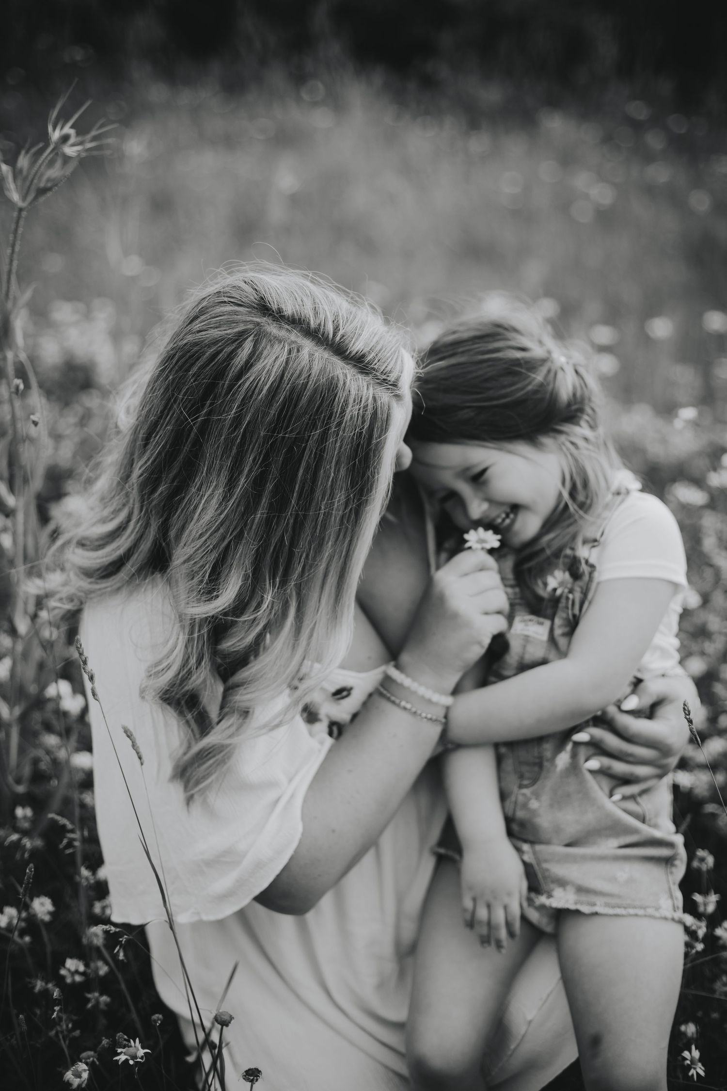 A tender black and white moment shared between parent and child in a wildflower field during summer.