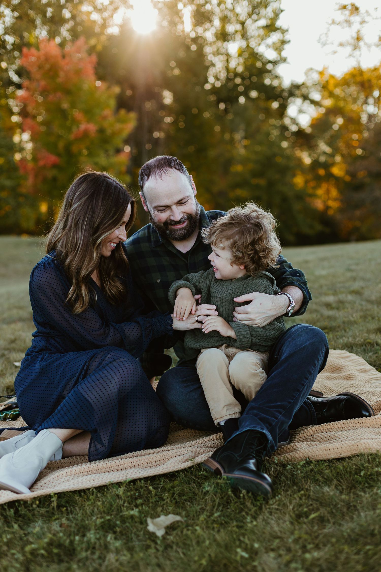 A family shares a tender moment while sitting together on a blanket during golden hour.