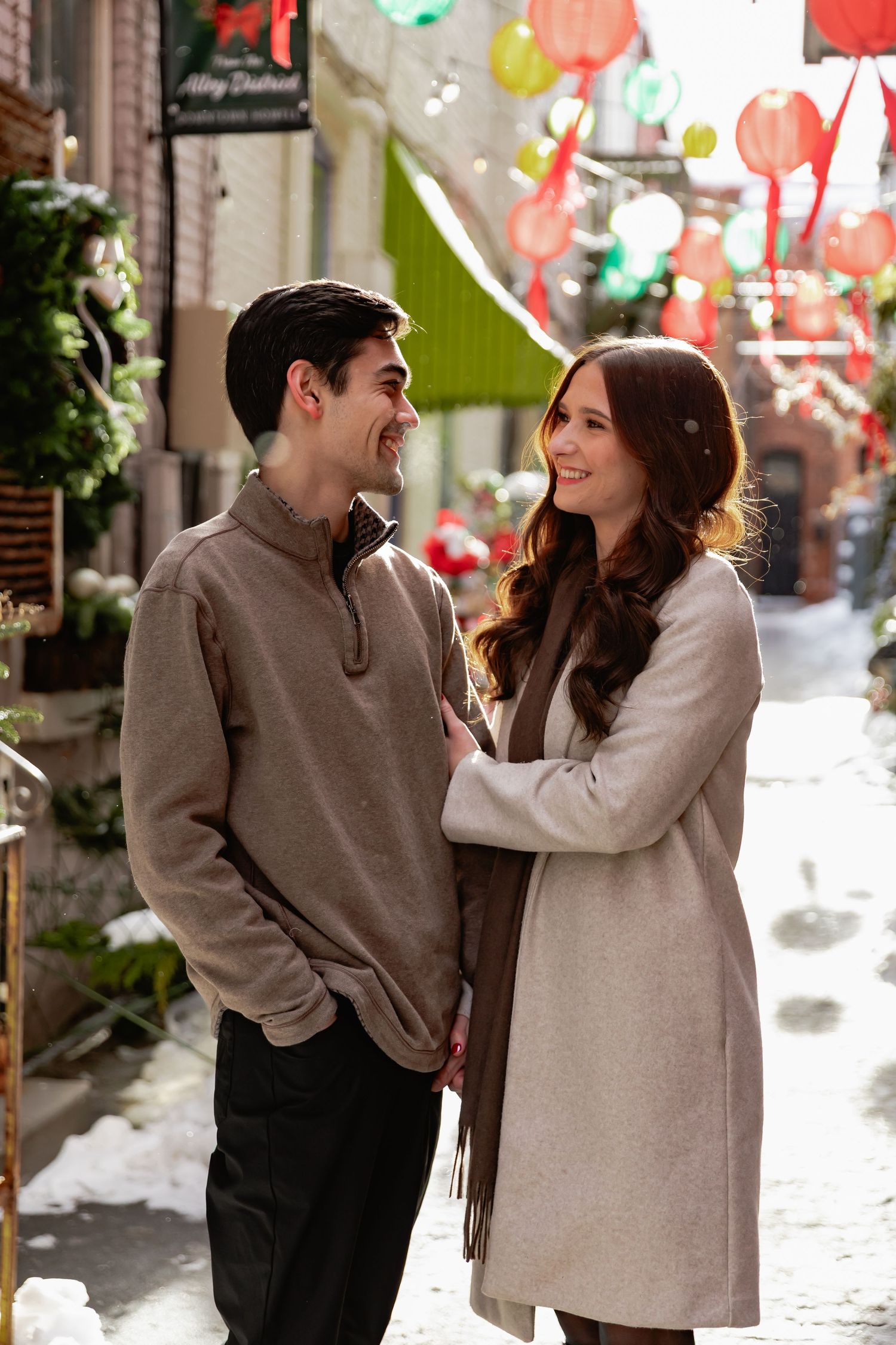 A couple shares a romantic moment under colorful paper lanterns in a snowy winter setting.