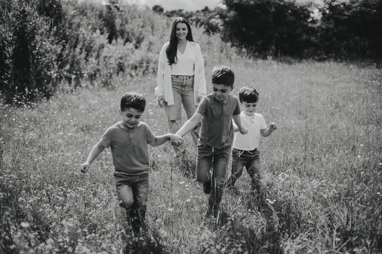 Children run and play together in a grassy meadow on a sunny summer day.