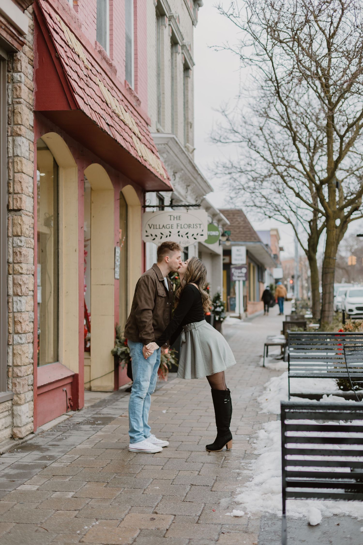 A couple shares an intimate moment on a charming small-town street in winter.