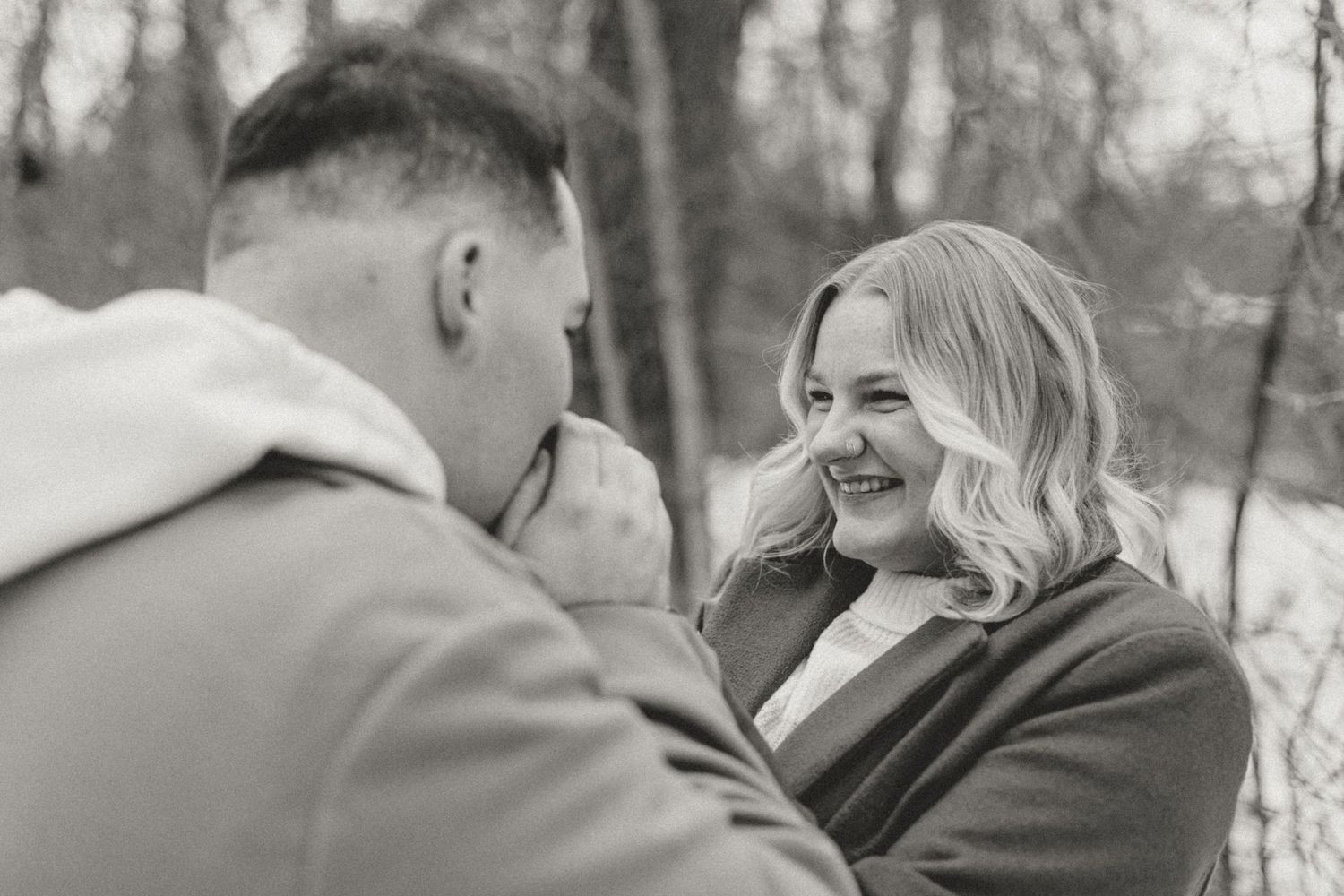 A couple shares a joyful moment together outdoors during a winter engagement photoshoot.