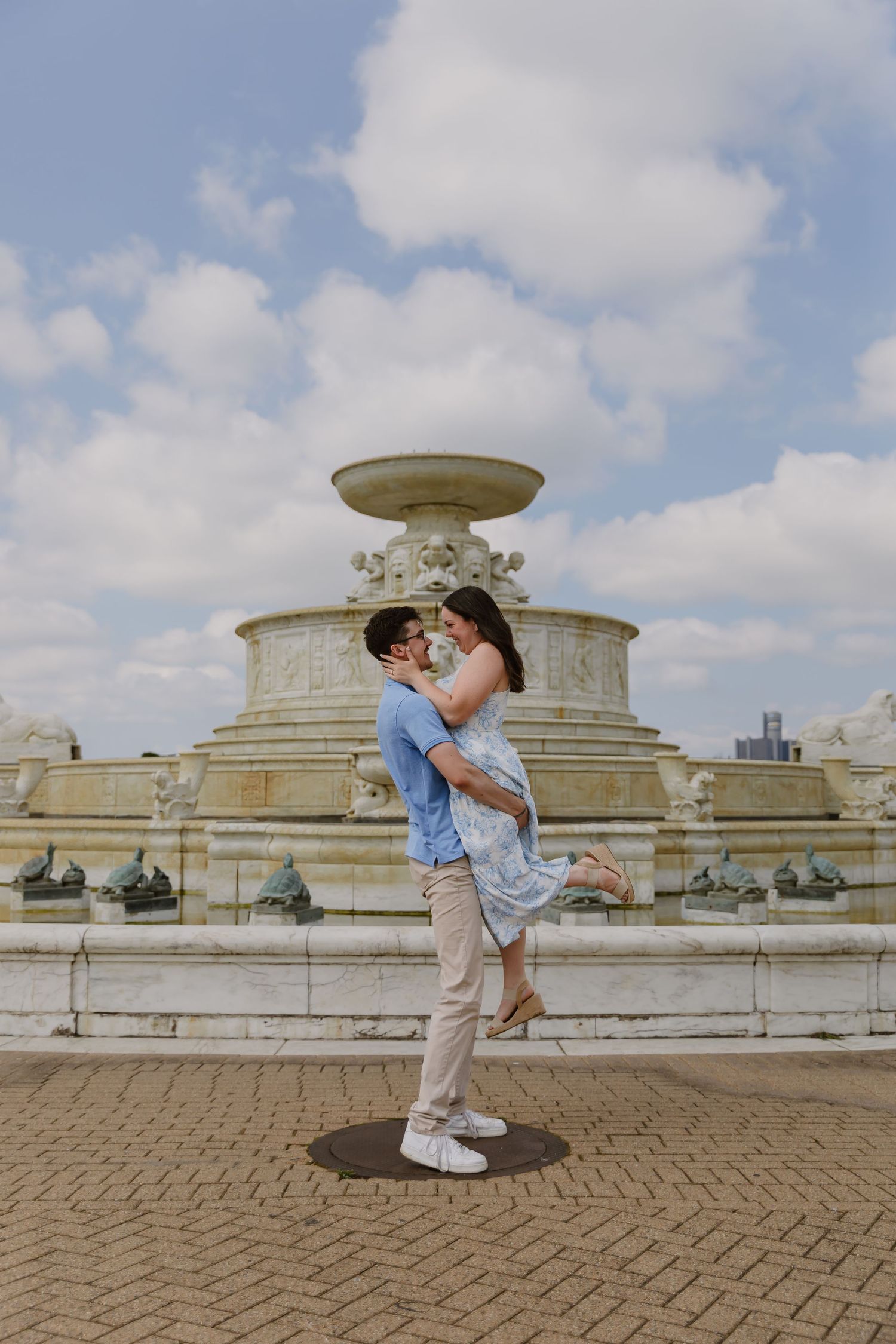 A romantic couple embraces in front of the Scott Memorial Fountain at Belle Isle Park in Detroit on a sunny day.