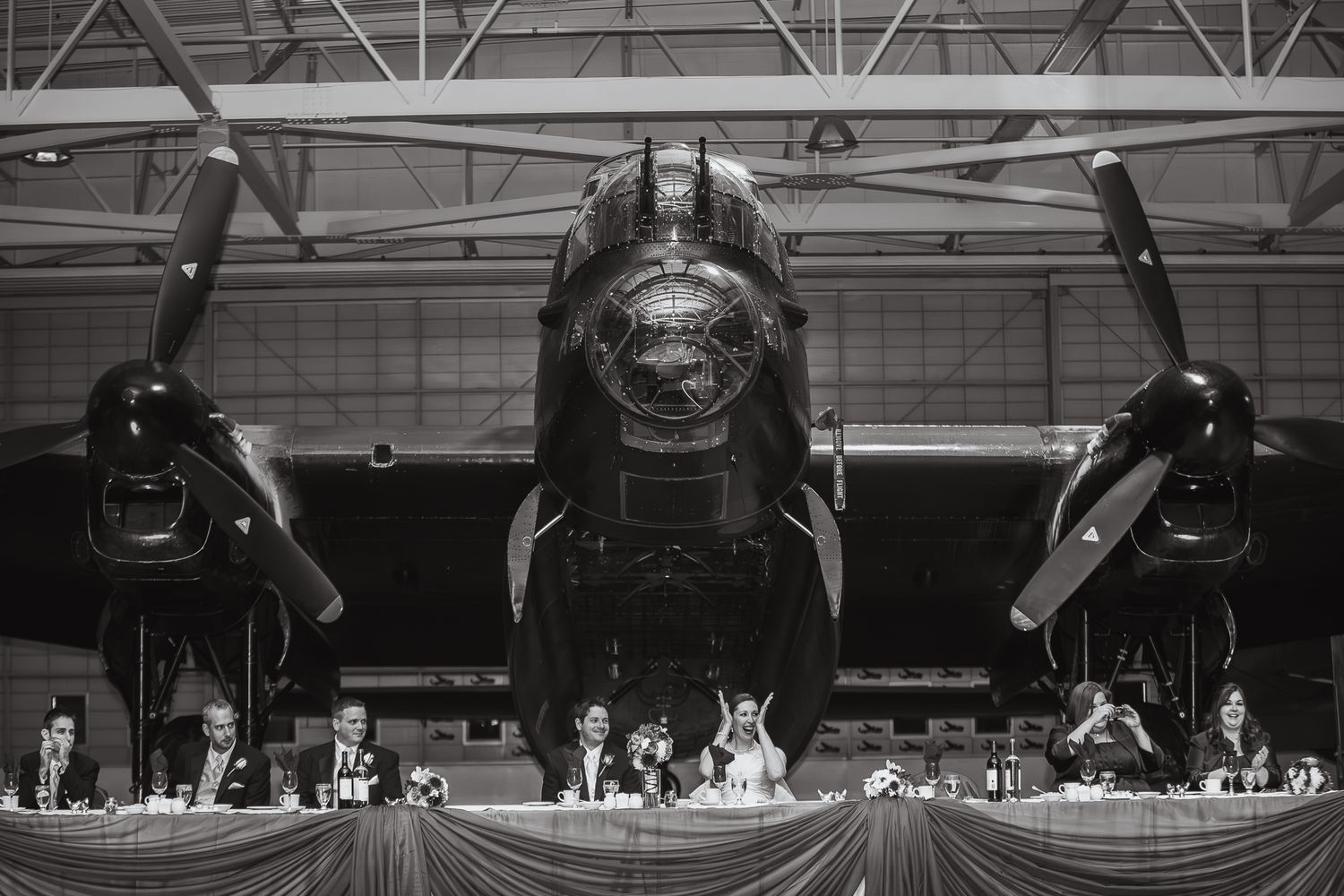 A vintage black and white photograph of an aircraft bomber on display in a hangar with dramatic lighting.