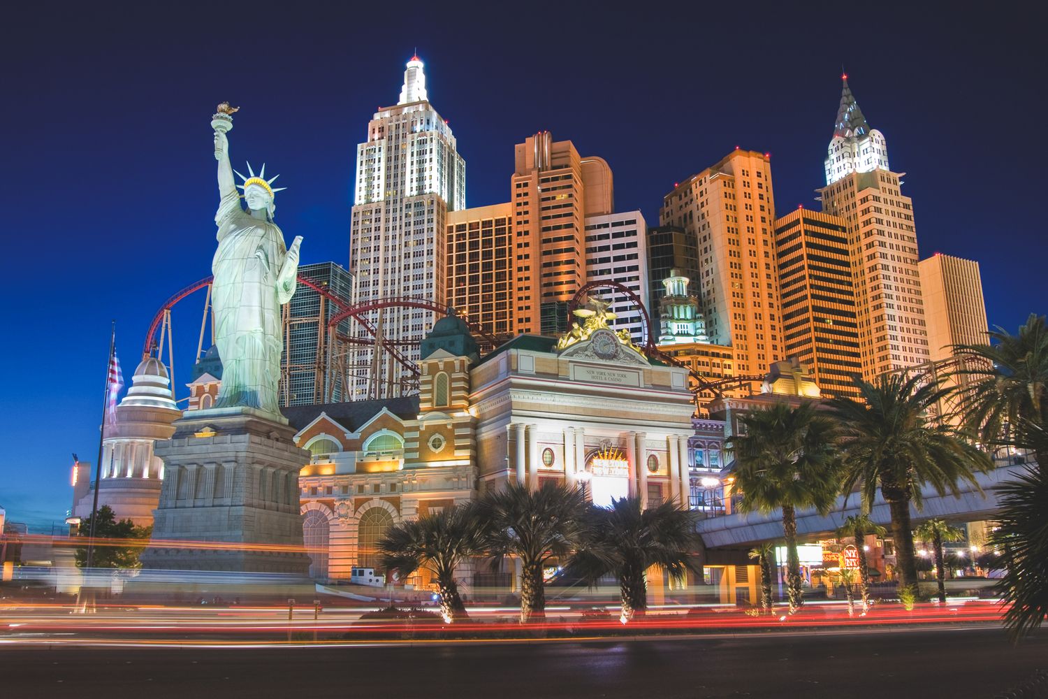 Las Vegas strip at night featuring New York-New York Hotel with illuminated Statue of Liberty replica.