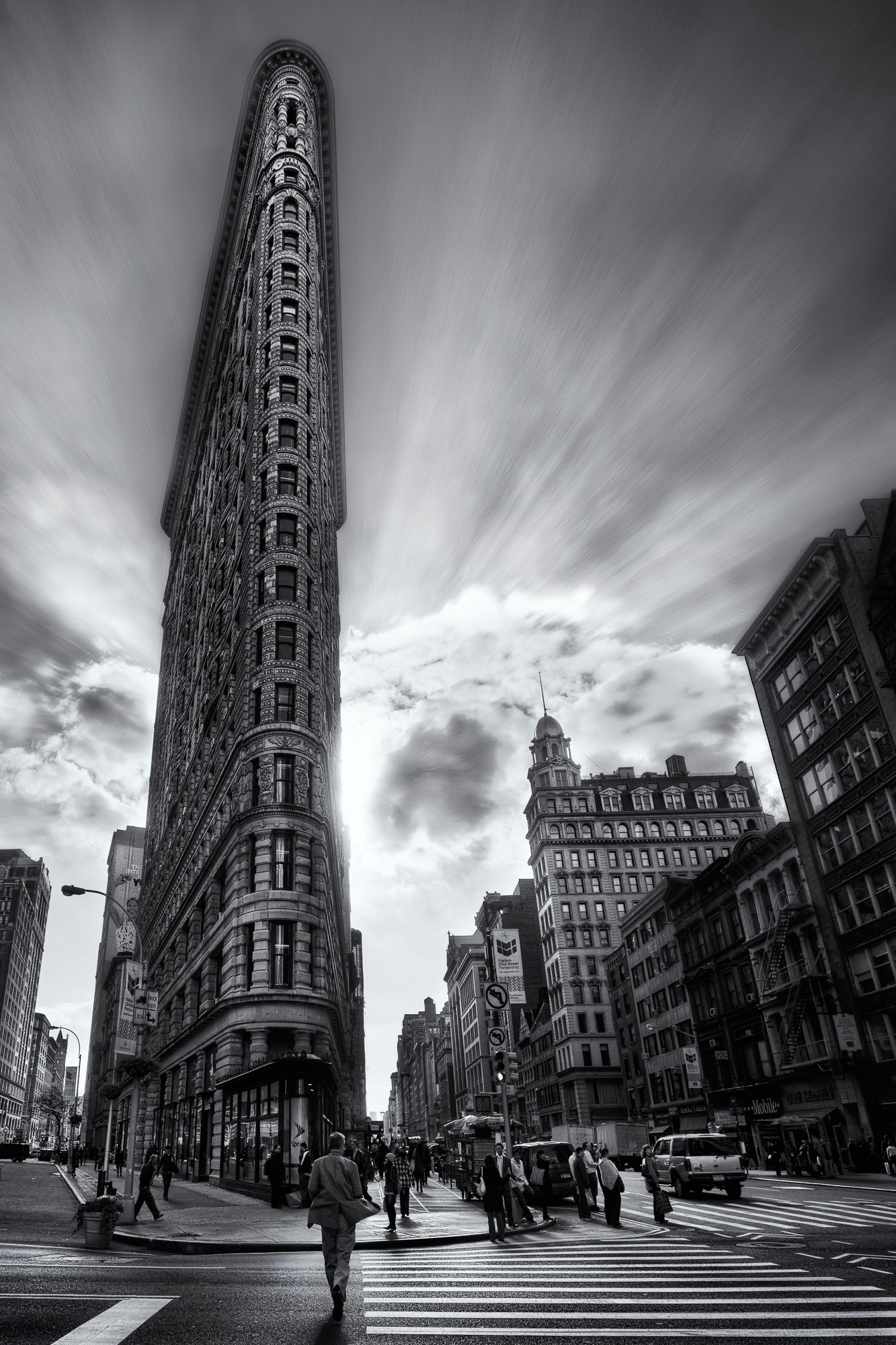 Black and white image of the historic Flatiron Building in New York City under dramatic clouds.