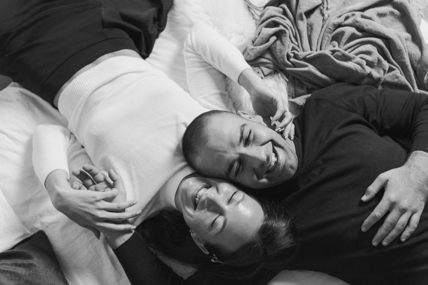 Candid and cinematic black and white portrait of a couple lying together and laughing, captured in a joyful and intimate moment