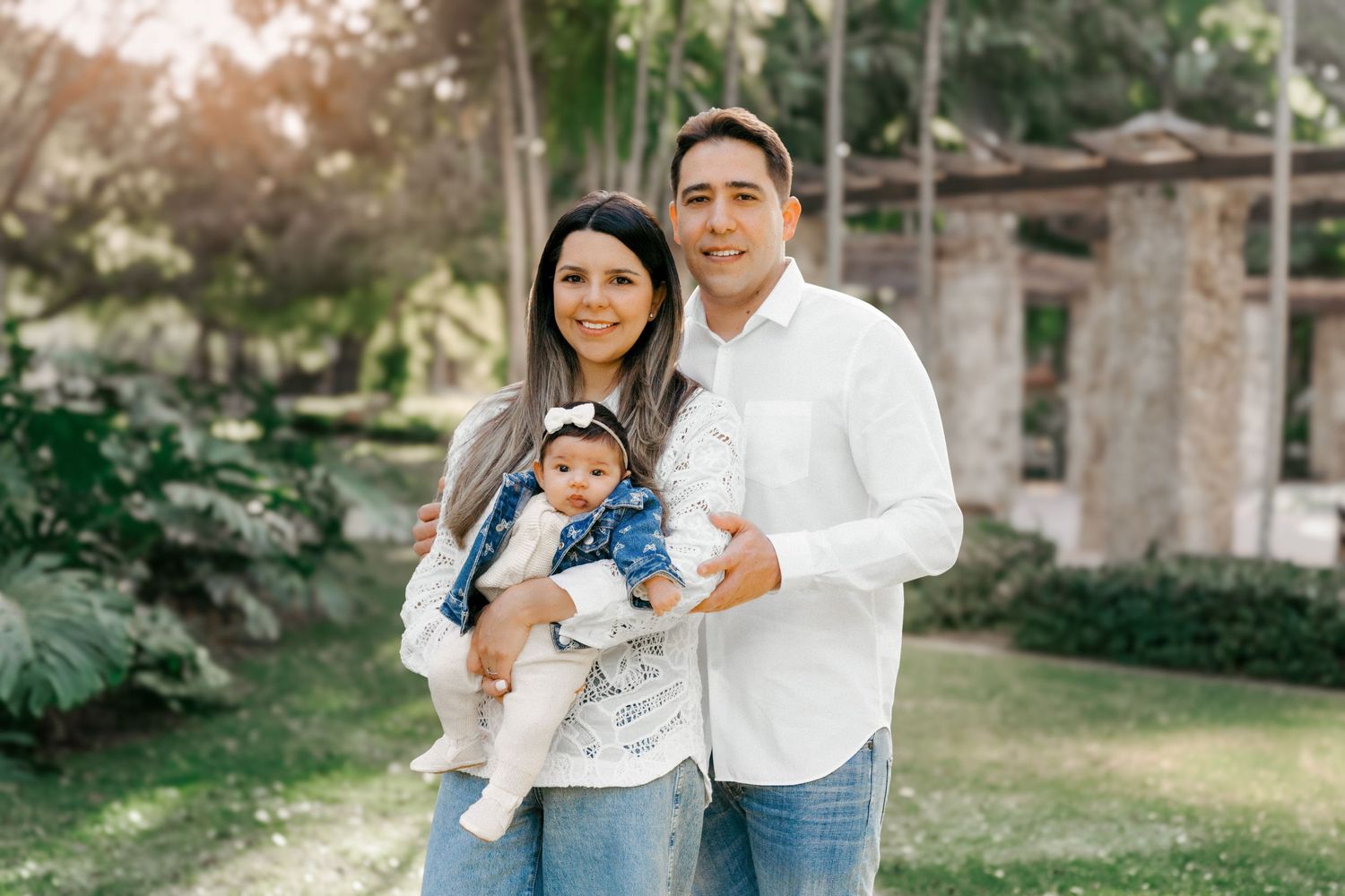 Parents with baby during a sunny family photo shoot in Miami, Florida.