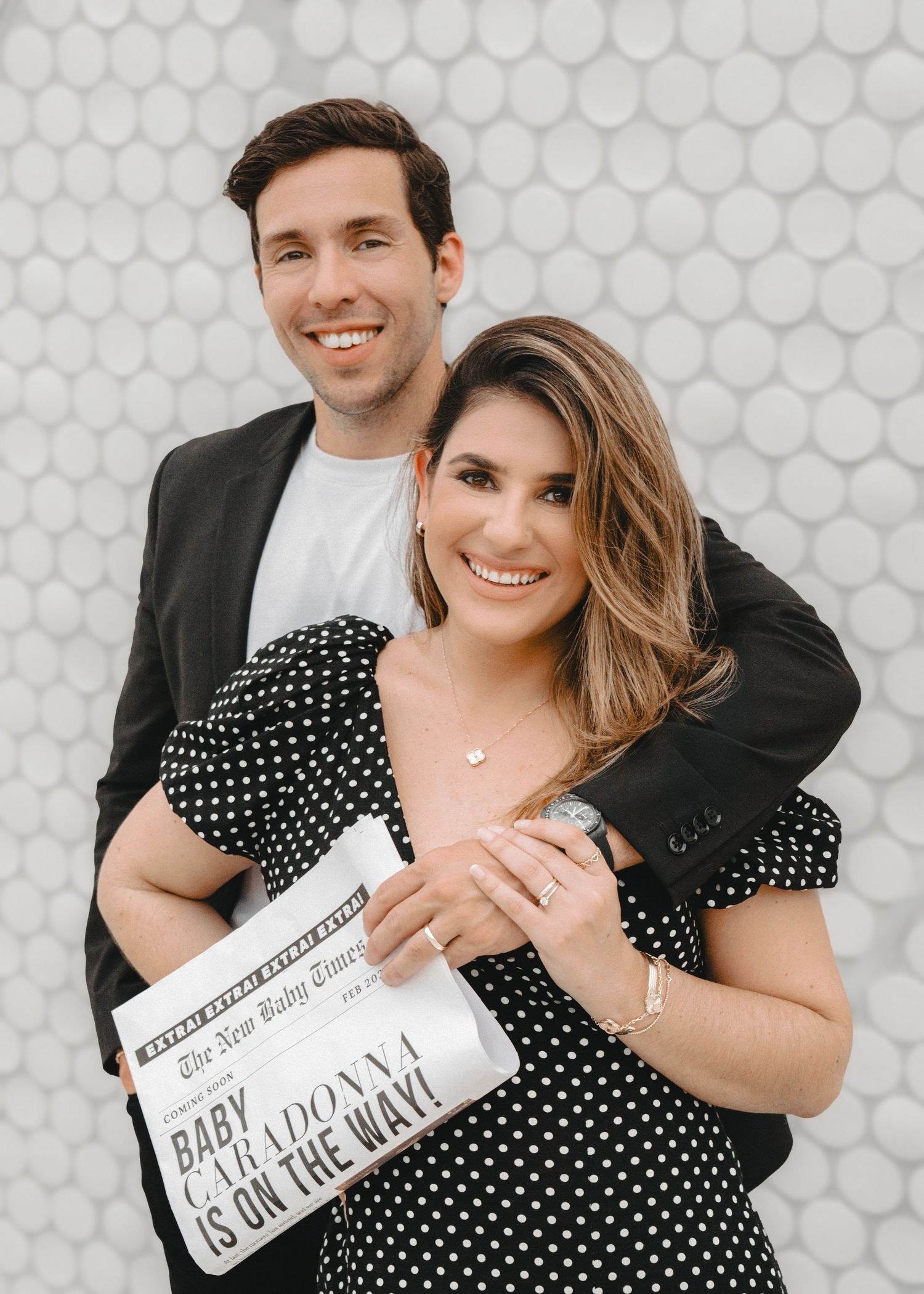 Maternity photoshoot in Miami – expecting couple smiling and holding a pregnancy announcement newspaper