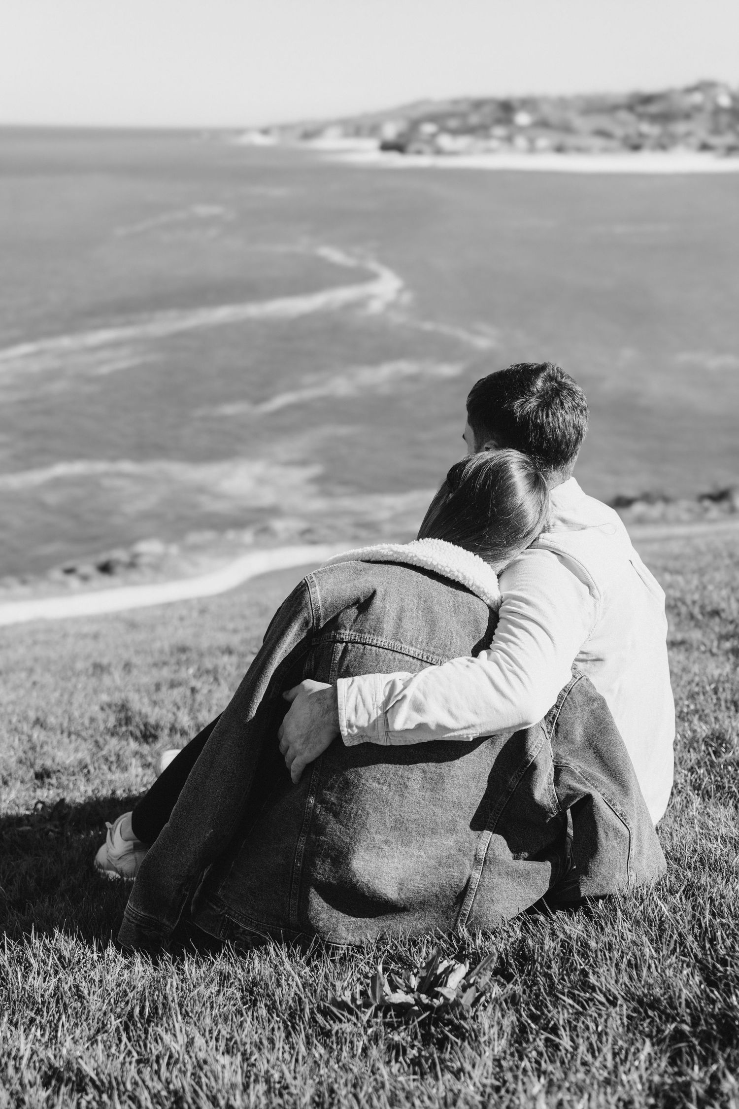 Romantic couple sitting on a hillside overlooking the ocean during a cinematic lifestyle photoshoot