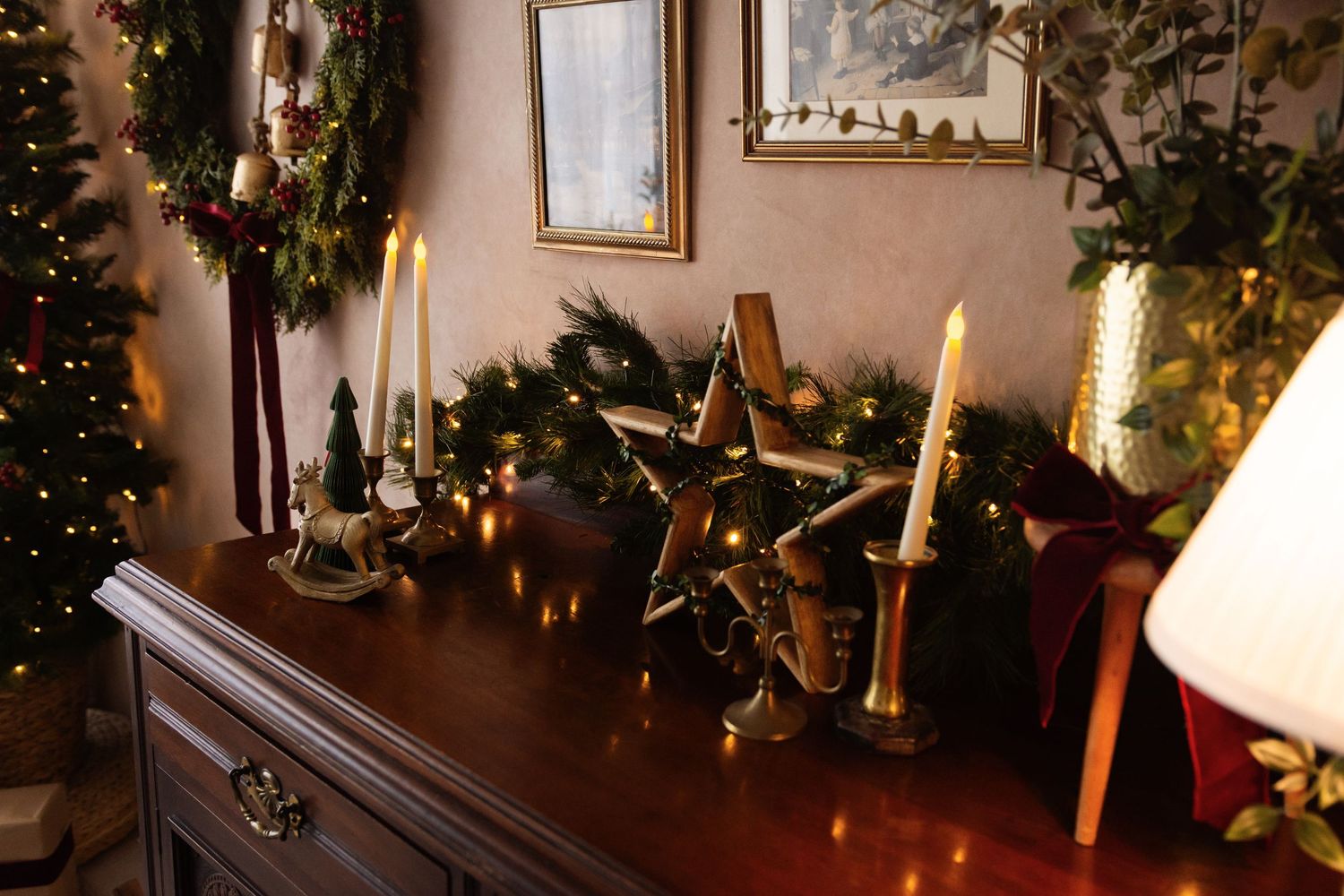 Festive Christmas dresser display with gold star, candles, and garland decorations in a cozy holiday home setting.