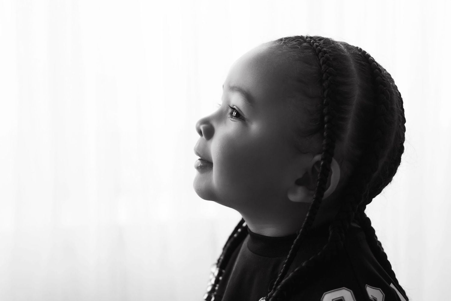 Black and white profile portrait of a young girl with braided hair looking upward.