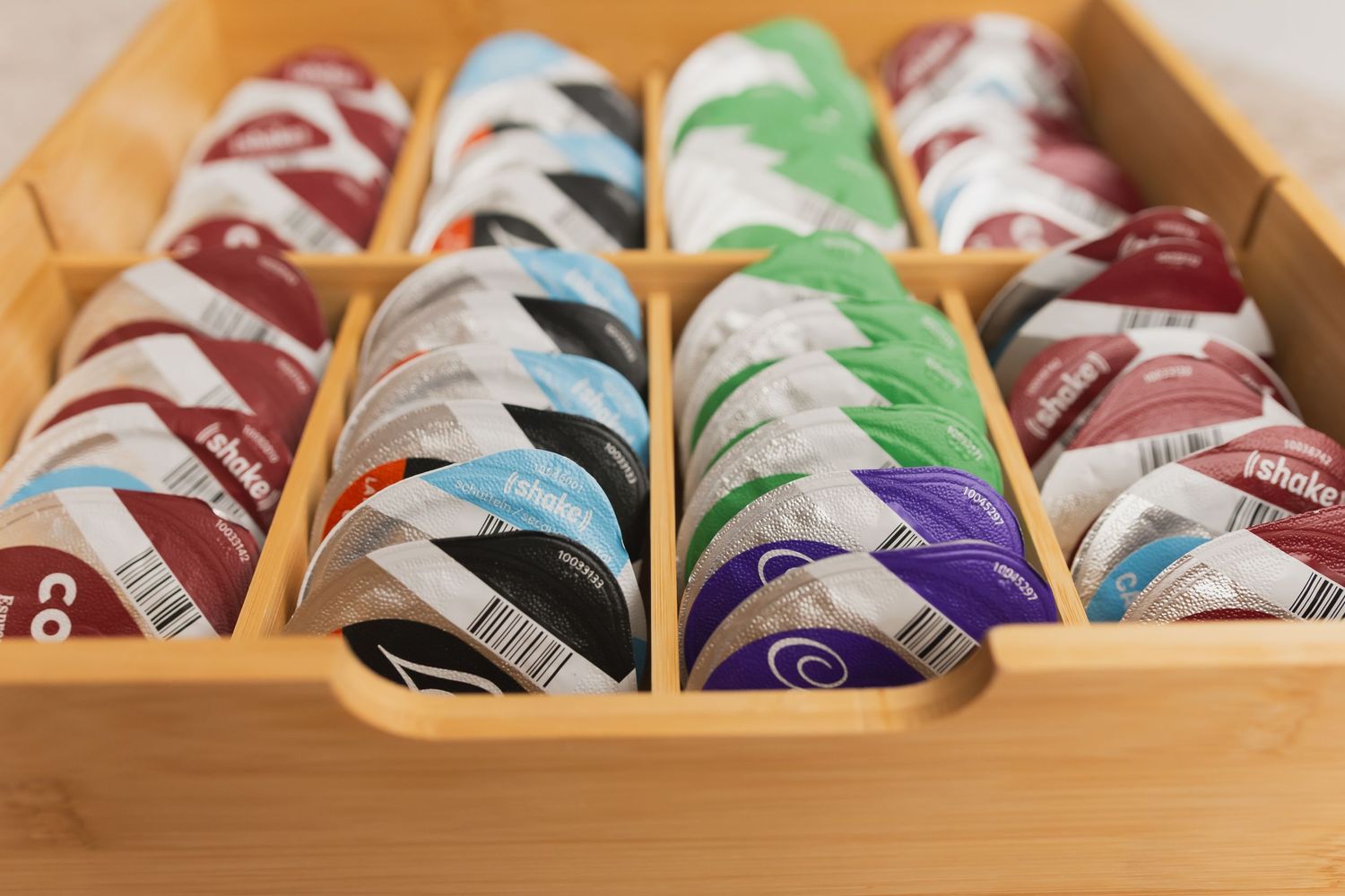 Bamboo drawer organizer neatly storing various colorful round tin containers in multiple rows.