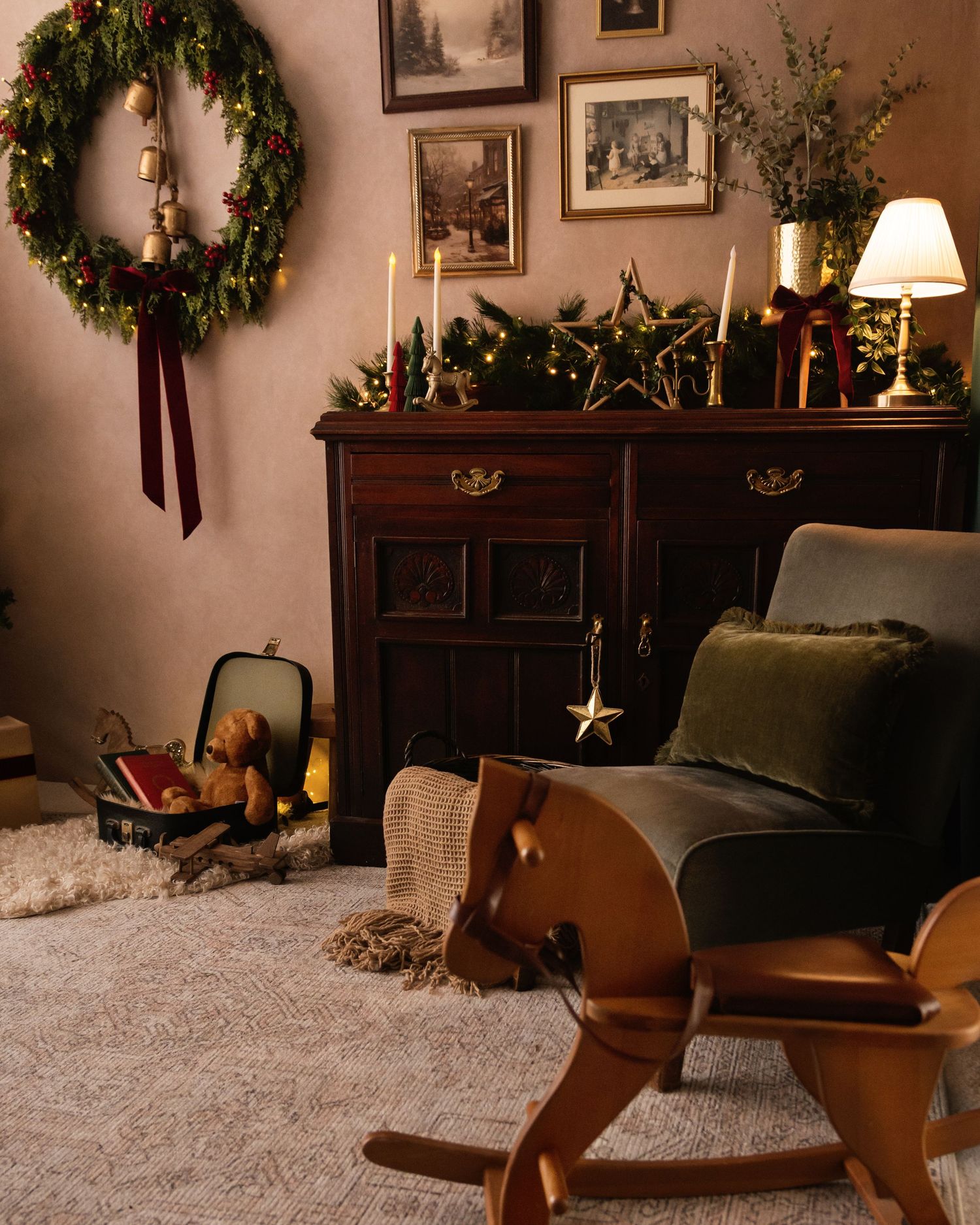 Cozy Christmas living room with wreath, decorated dresser, candles, green armchair, and wooden rocking horse on carpet.