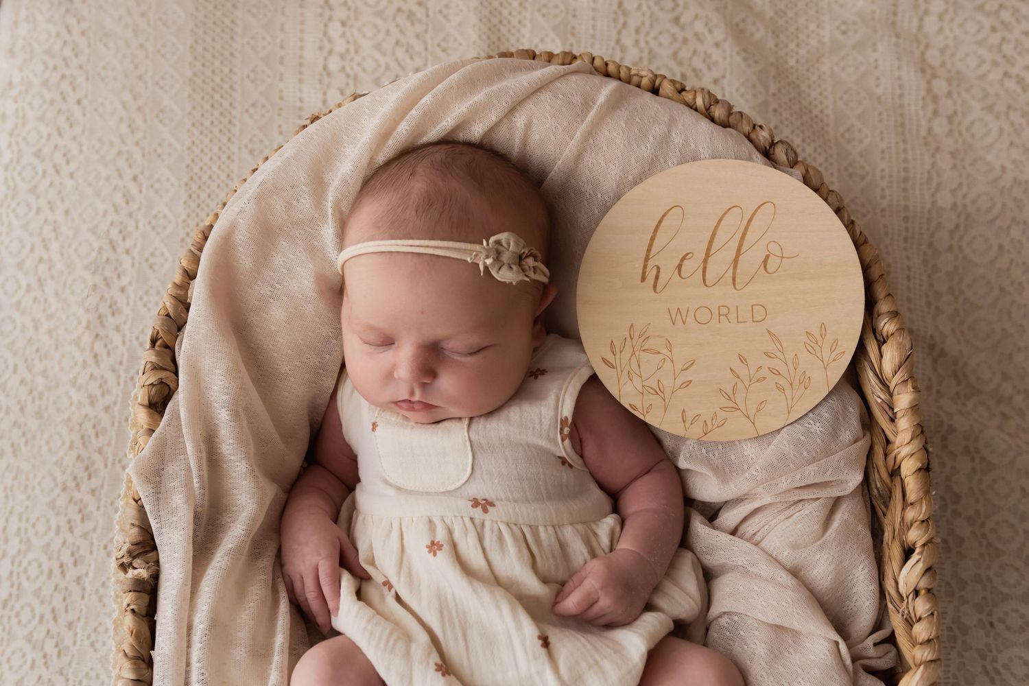 Sleeping newborn baby with hello world wooden sign in wicker basket.