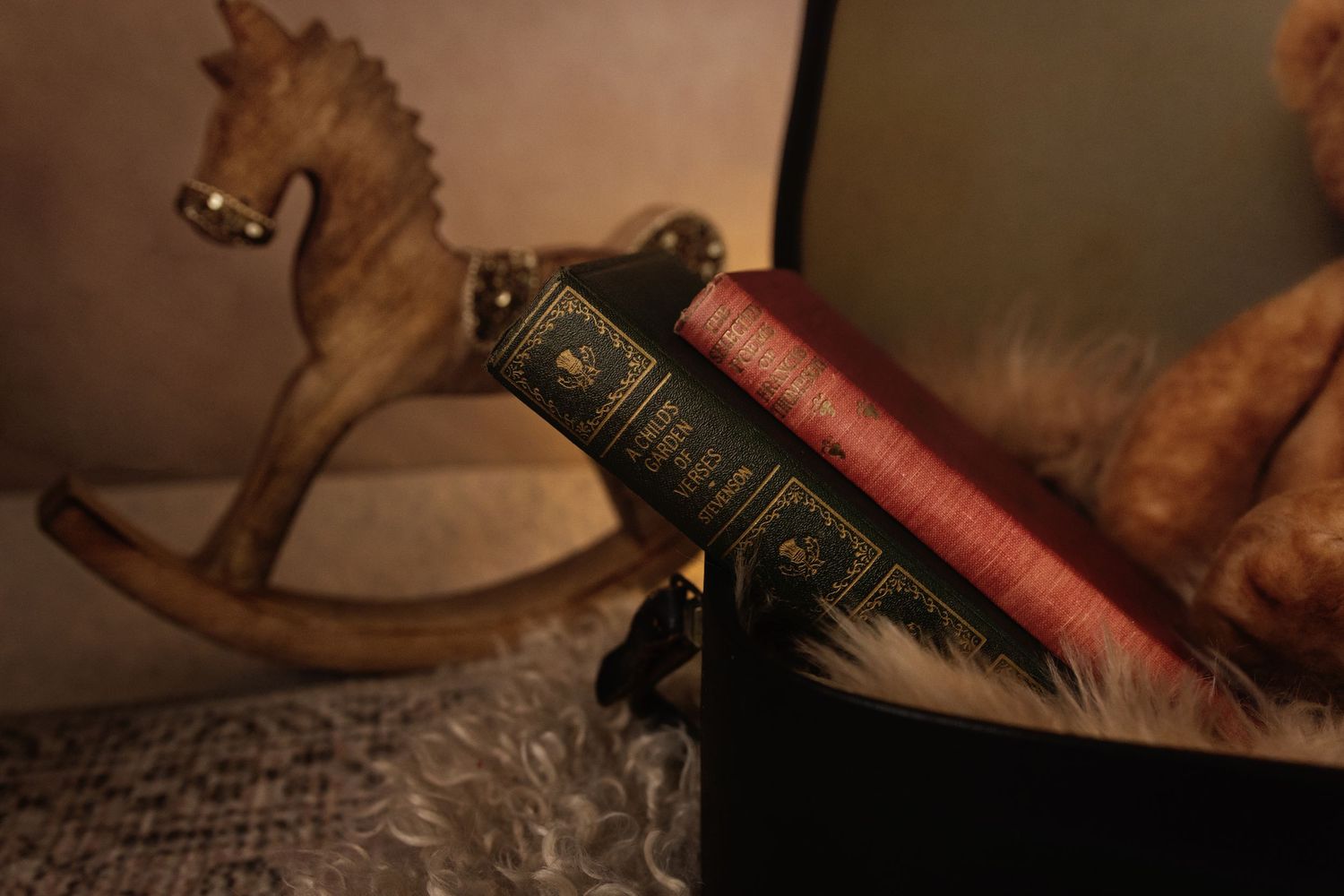 Vintage rocking horse figurine beside antique leather-bound books and a teddy bear in warm, nostalgic lighting.