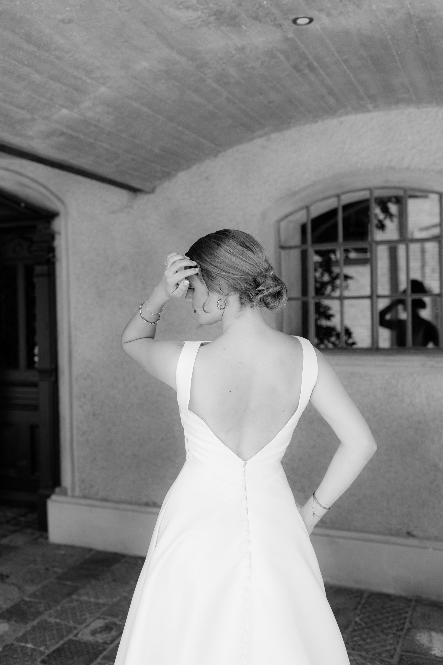 A series of black and white photos showing the back of a bride in a white wedding dress in various poses.