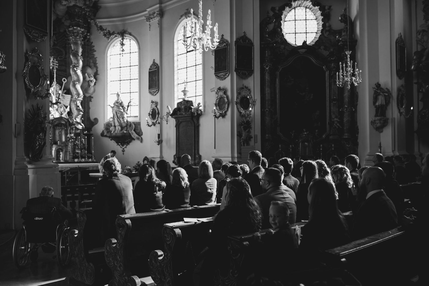 Black and white panoramic view of a church interior with people gathered in pews during a ceremony.