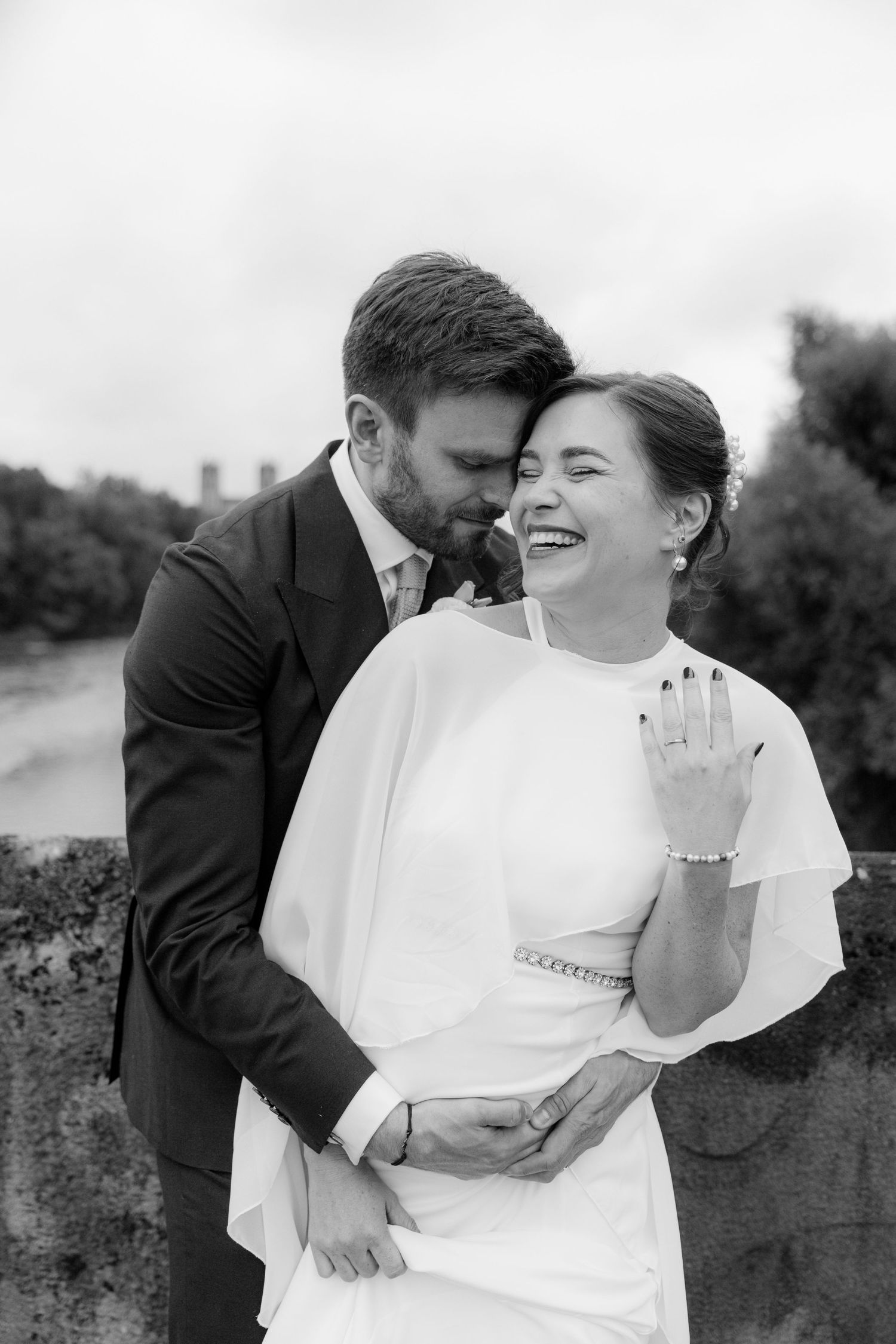 Black and white wedding photos show intimate moments between newlyweds embracing and laughing together outdoors.