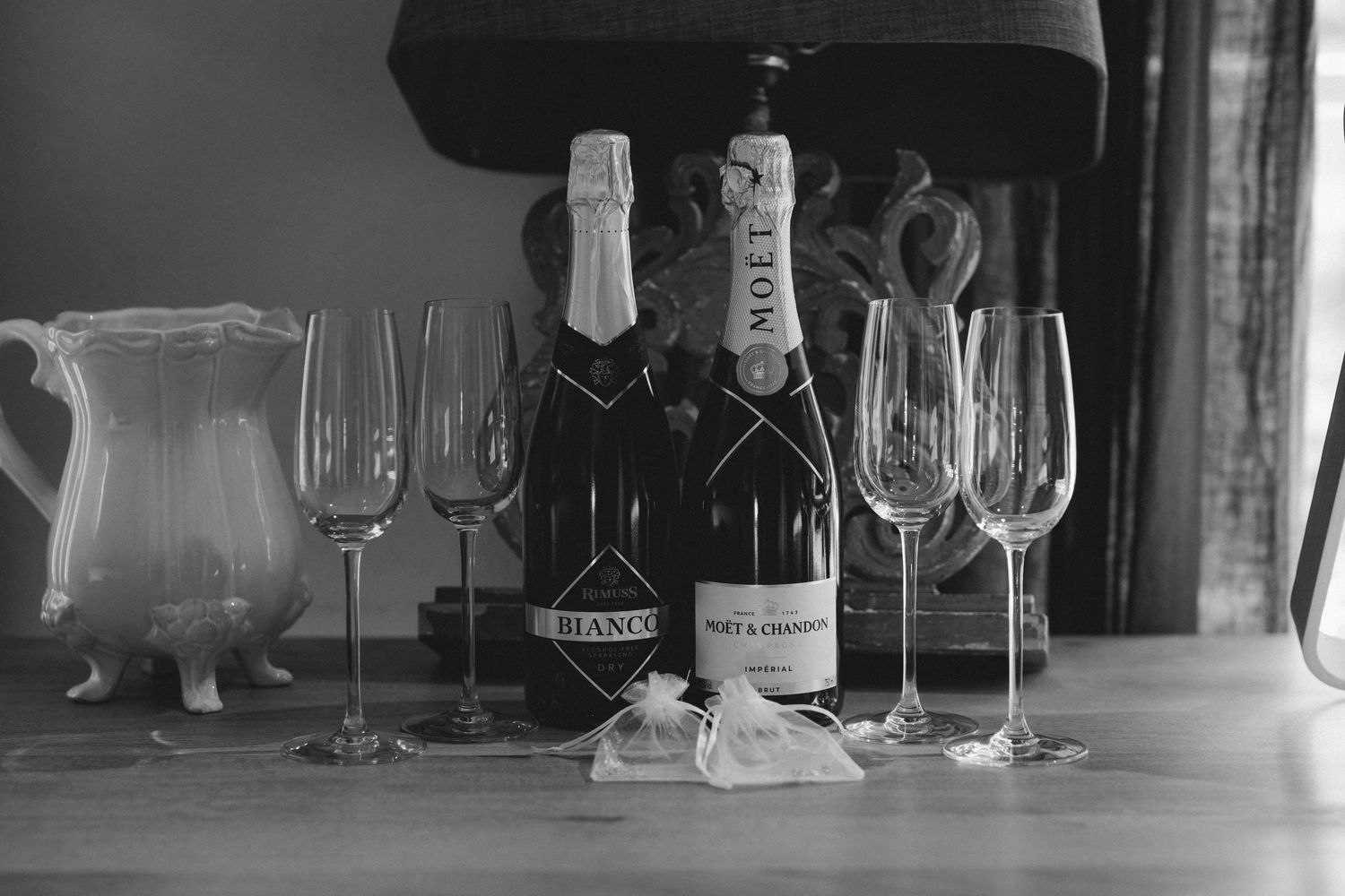 Wine glasses and bottles arranged in a row on a dark background with soft lighting and reflective surfaces.