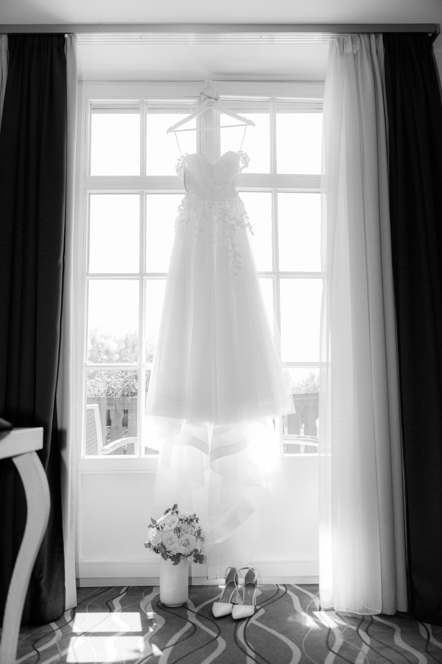 A series of black and white photos showing a wedding dress hanging in front of sunlit windows with sheer curtains.