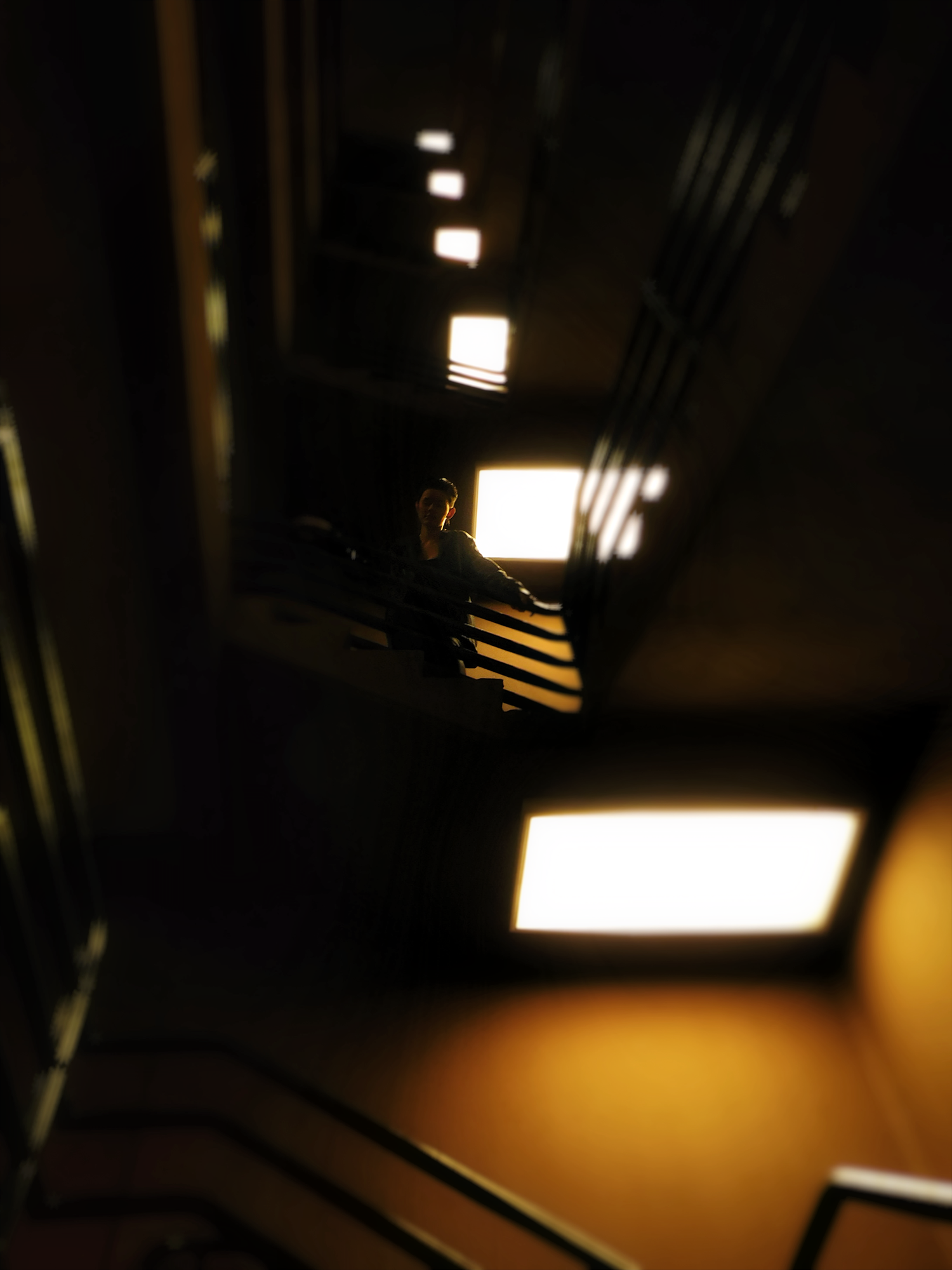 Dark moody stairwell with glowing square ceiling lights casting warm golden light on ascending steps.