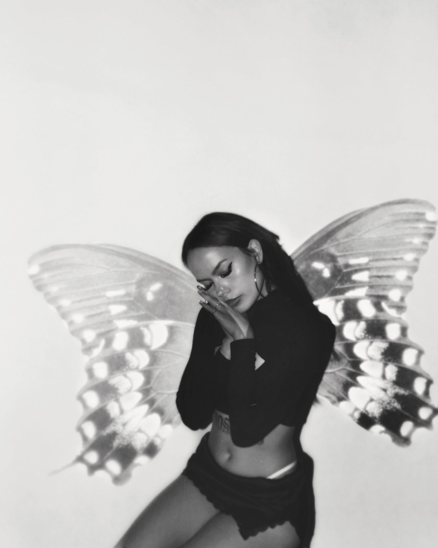 Black and white photo of a woman posing with butterfly wings double exposure effect.