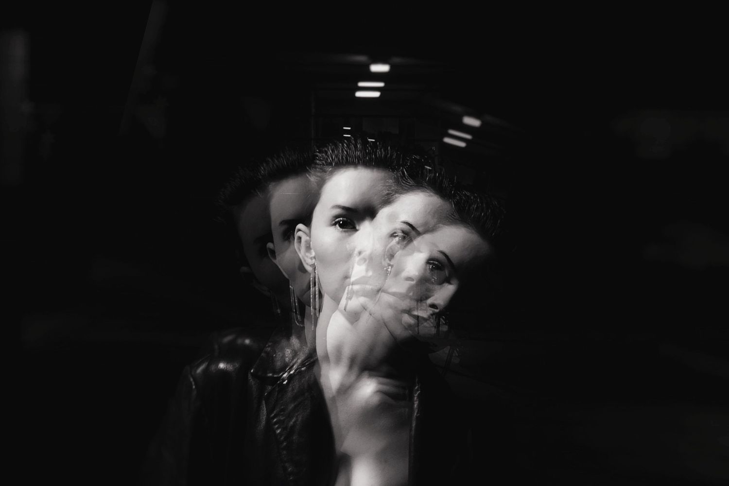 Black and white multiple exposure portrait of a woman wearing a crown in dark surroundings.