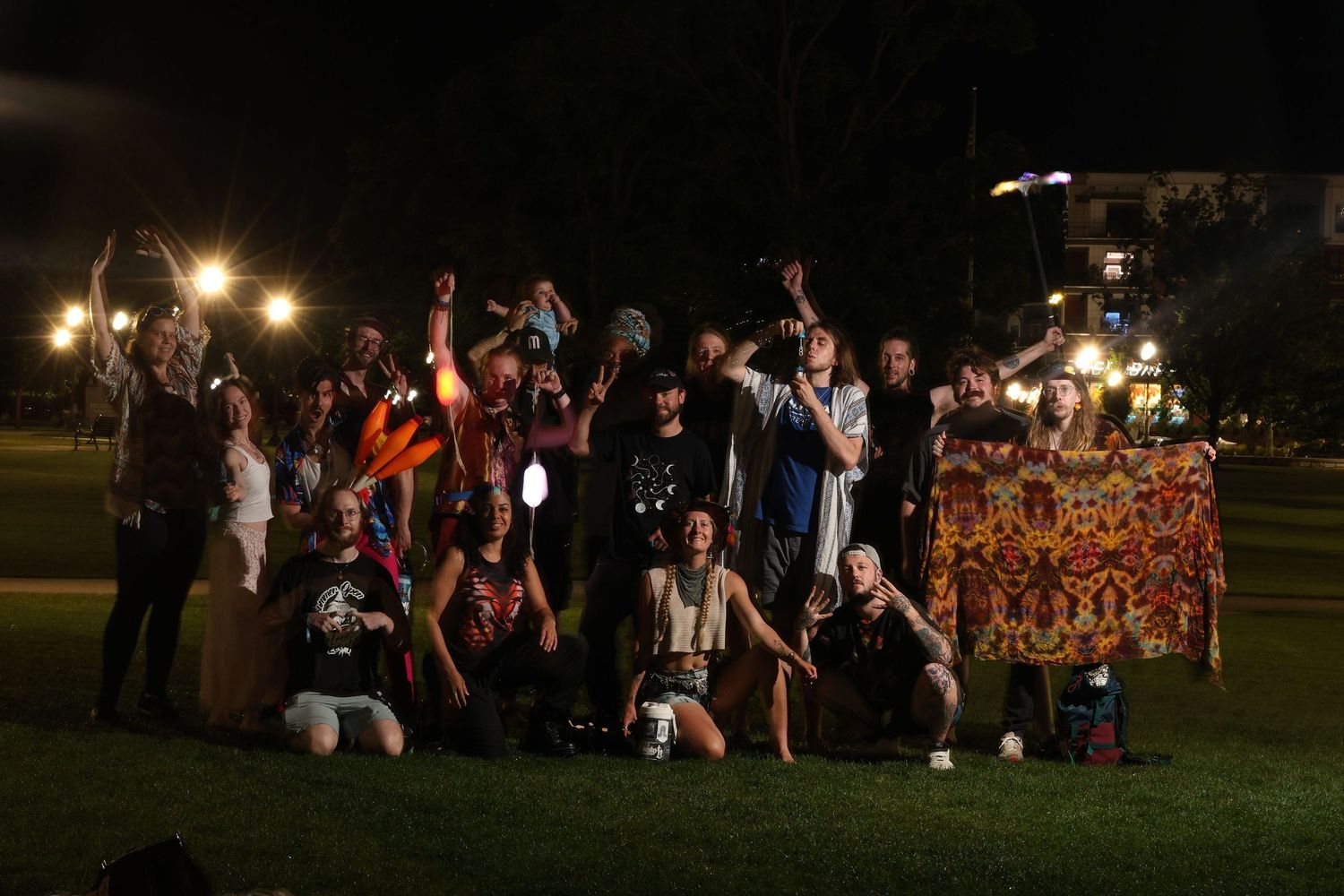 A group of people gathered outdoors at night holding signs and posing for a photo on a grassy field.