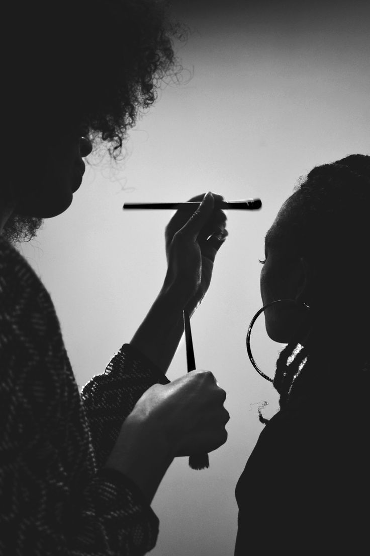 Black and white silhouette of two figures in profile with one holding a pen or writing instrument.