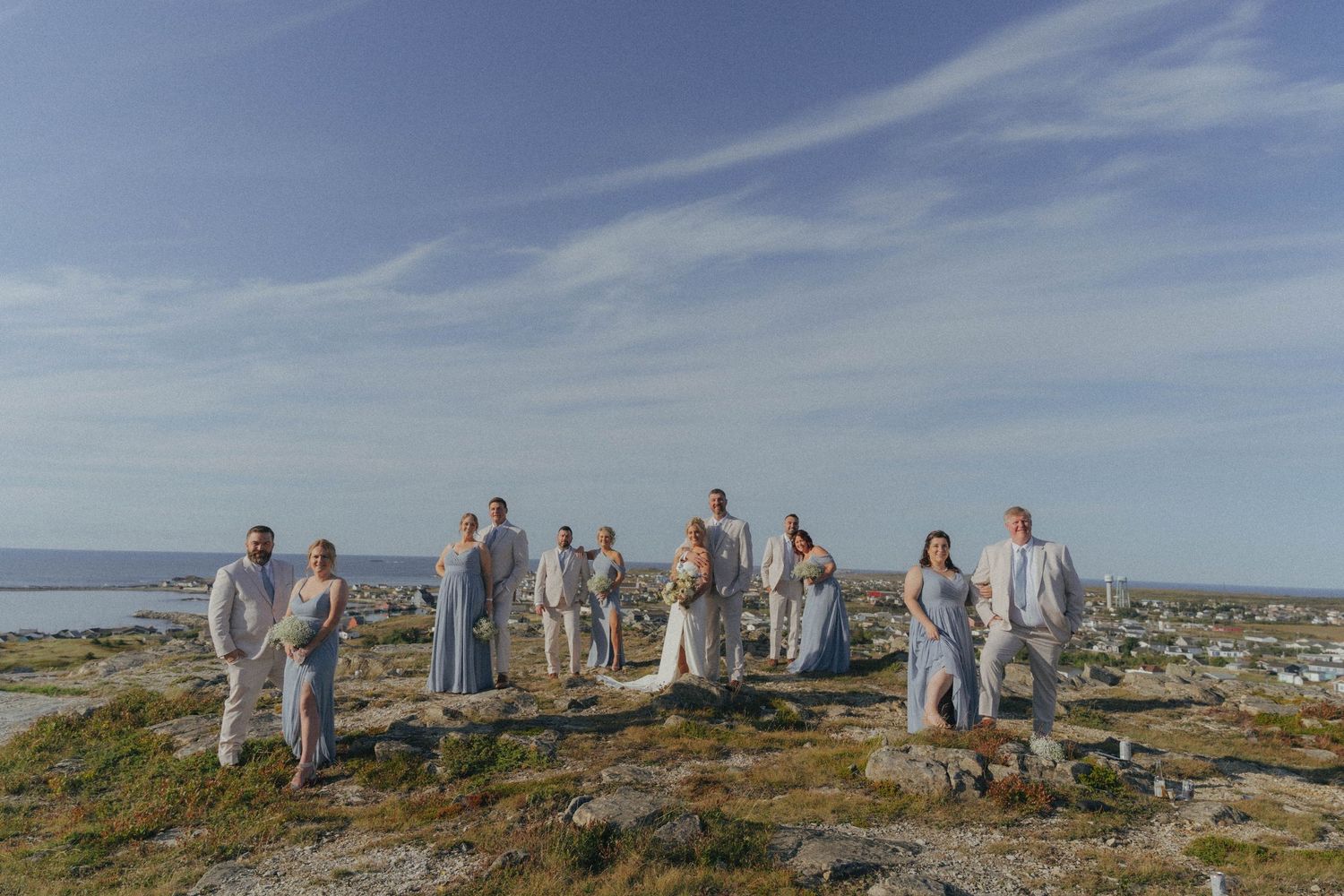 Wedding guests gathered on a scenic coastal bluff with ocean views in the background.