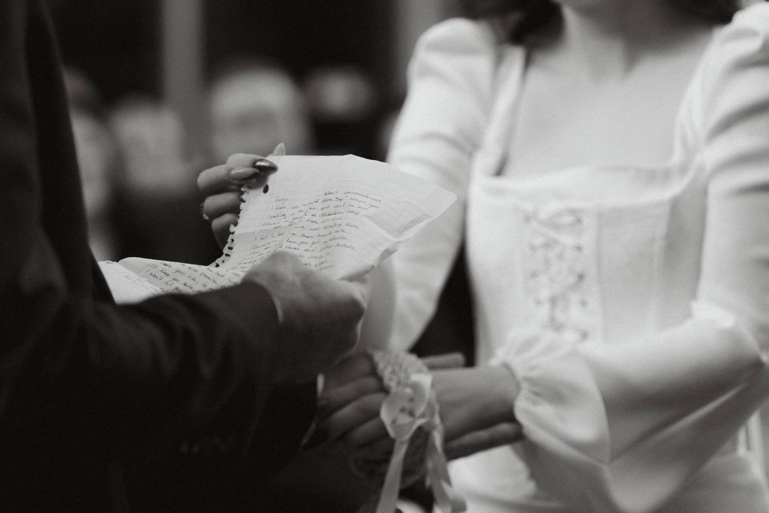 Black and white close-up image of hands exchanging wedding vows during a traditional ceremony.