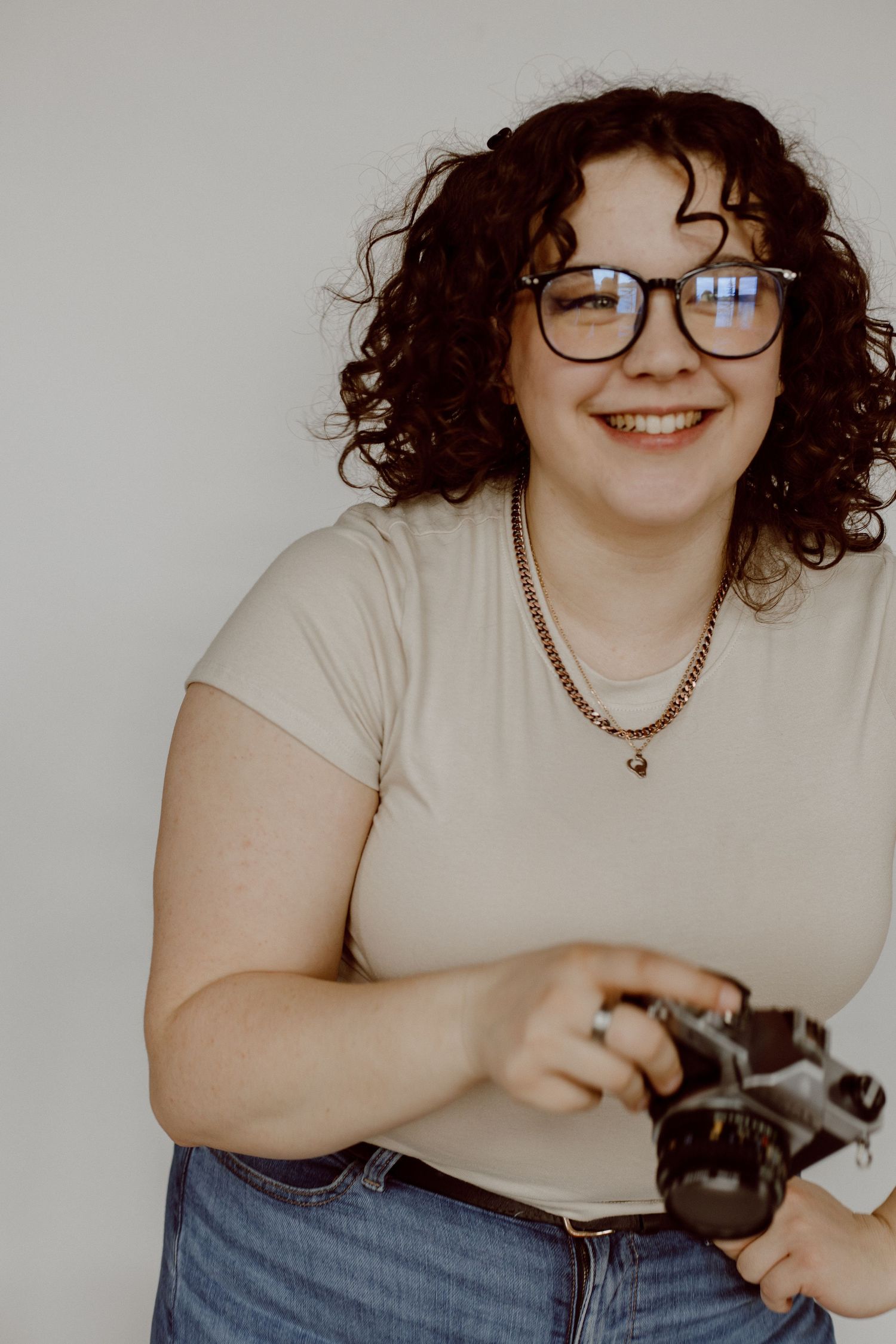Casual studio portraits with camera gear and cream colored top.