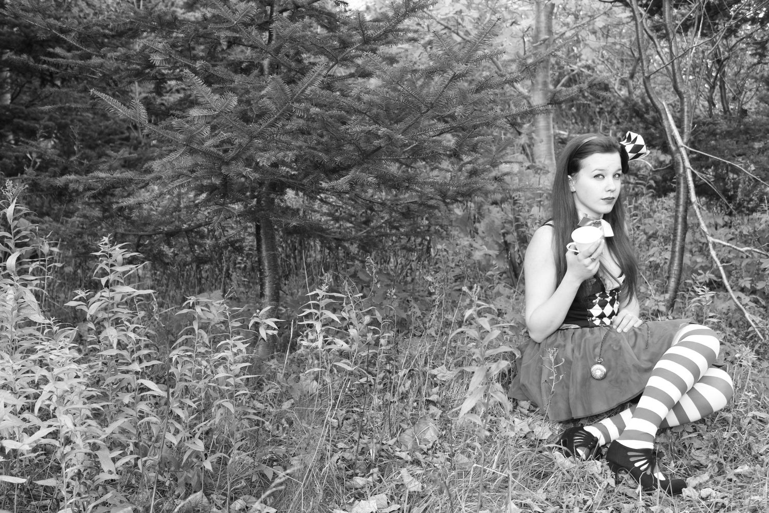 Black and white photo of someone exploring a forest path among tall trees.
