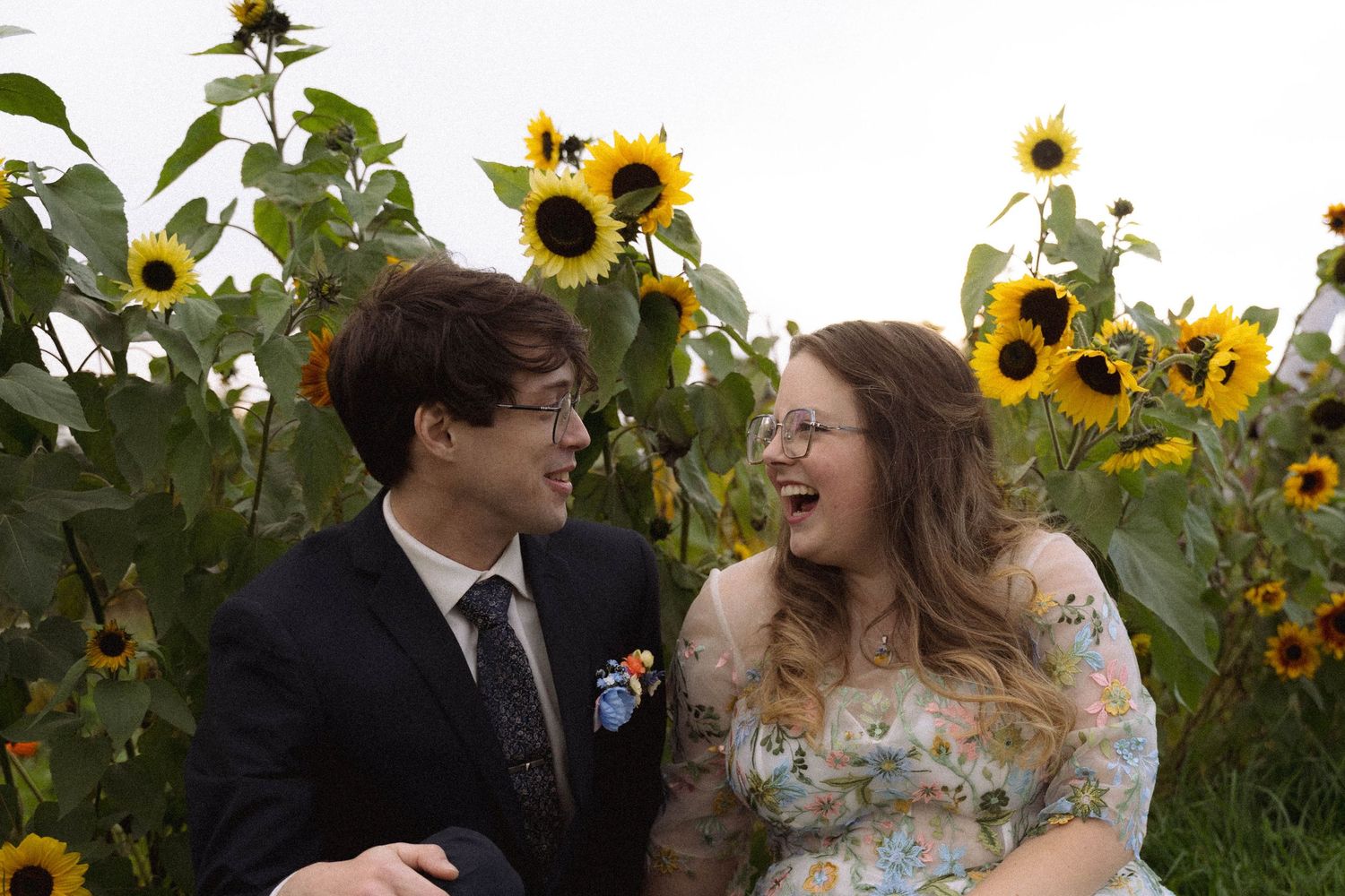 Newlyweds share a joyful moment among blooming sunflowers in a garden setting.