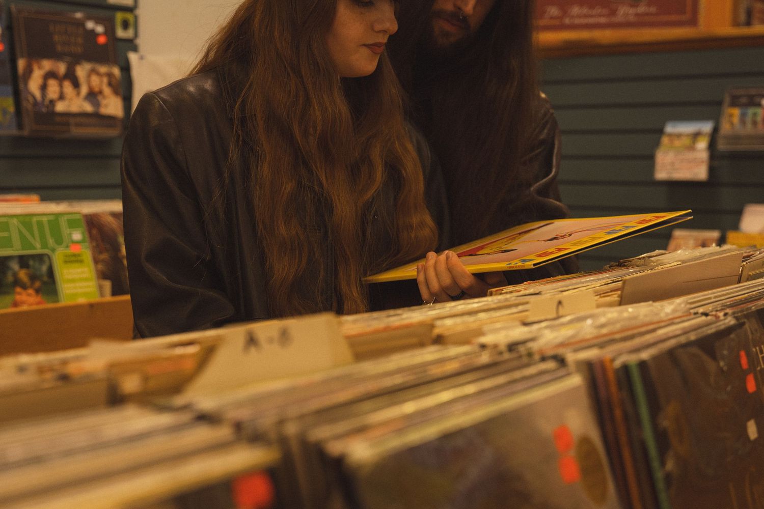 Vinyl records lined up in a record store with warm lighting.