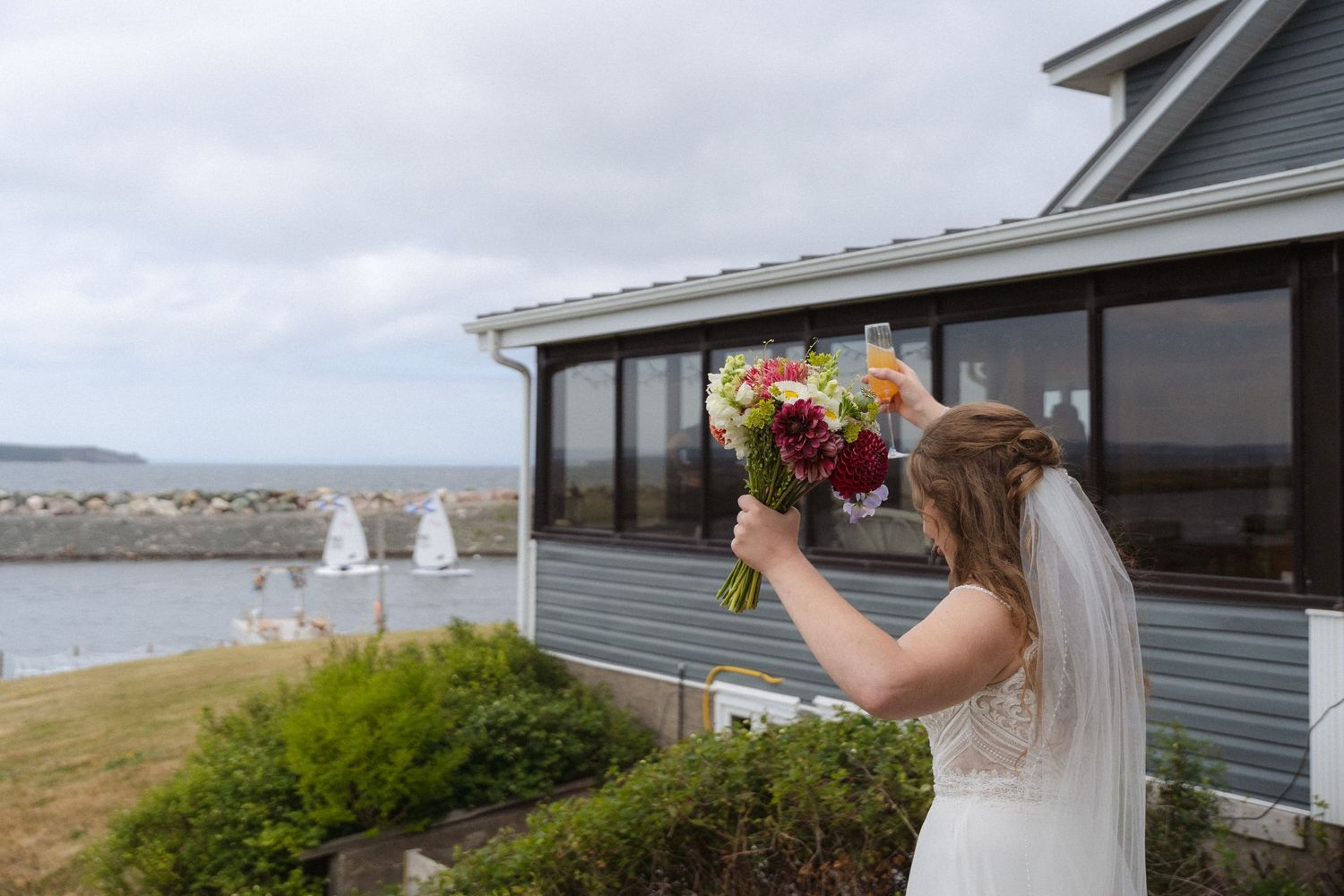 Coastal wedding venue with grey buildings overlooking the ocean on a cloudy day.